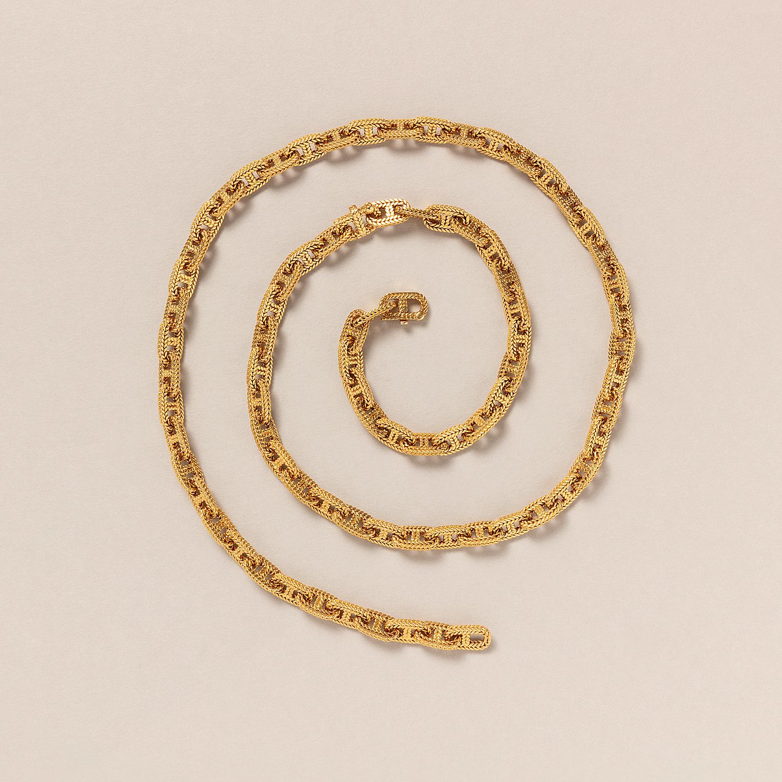 An 18 carat gold set consisting of a chain and bracelet designed to be worn individually or combined as one long chain featuring large, oval, woven links with concealed locks both signed: Hermès Paris, necklace 54603, bracelet 34603, each with a