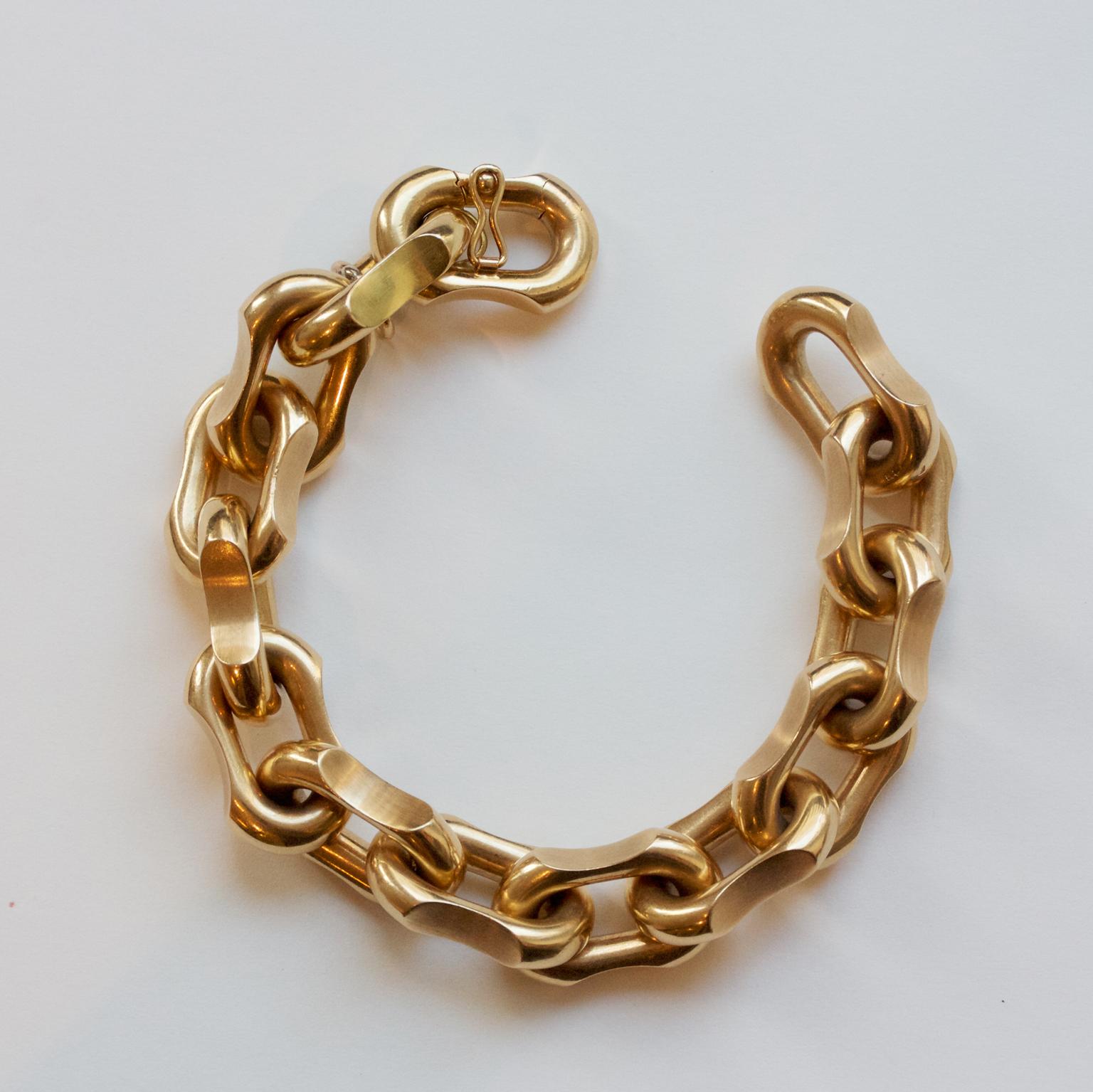 An 18 carat gold bracelet with high polished oval links with matte notches on each side, an invisible lock and a large fixed oval bail for a charm, master mark France, 1970.

length: 20 cm
width: 1.5 cm
weight: 66 gram