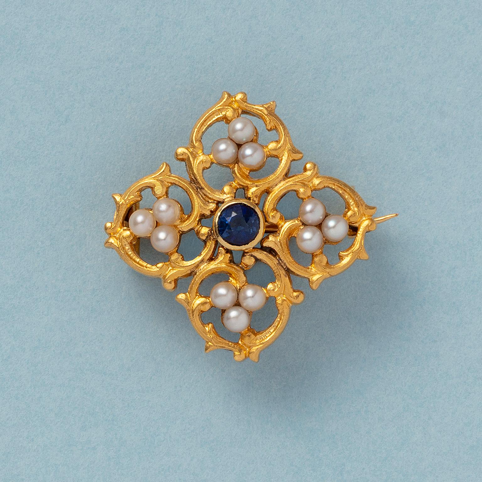 An 18 carat gold brooch with a quattre foil motive made of gold curls, in each curl are three natural pearls, in the heart of the brooch is a sapphire (app. 0.3 carat), France, circa 1870, with a French mastermark.

weight: 5.46 grams
dimensions: 25