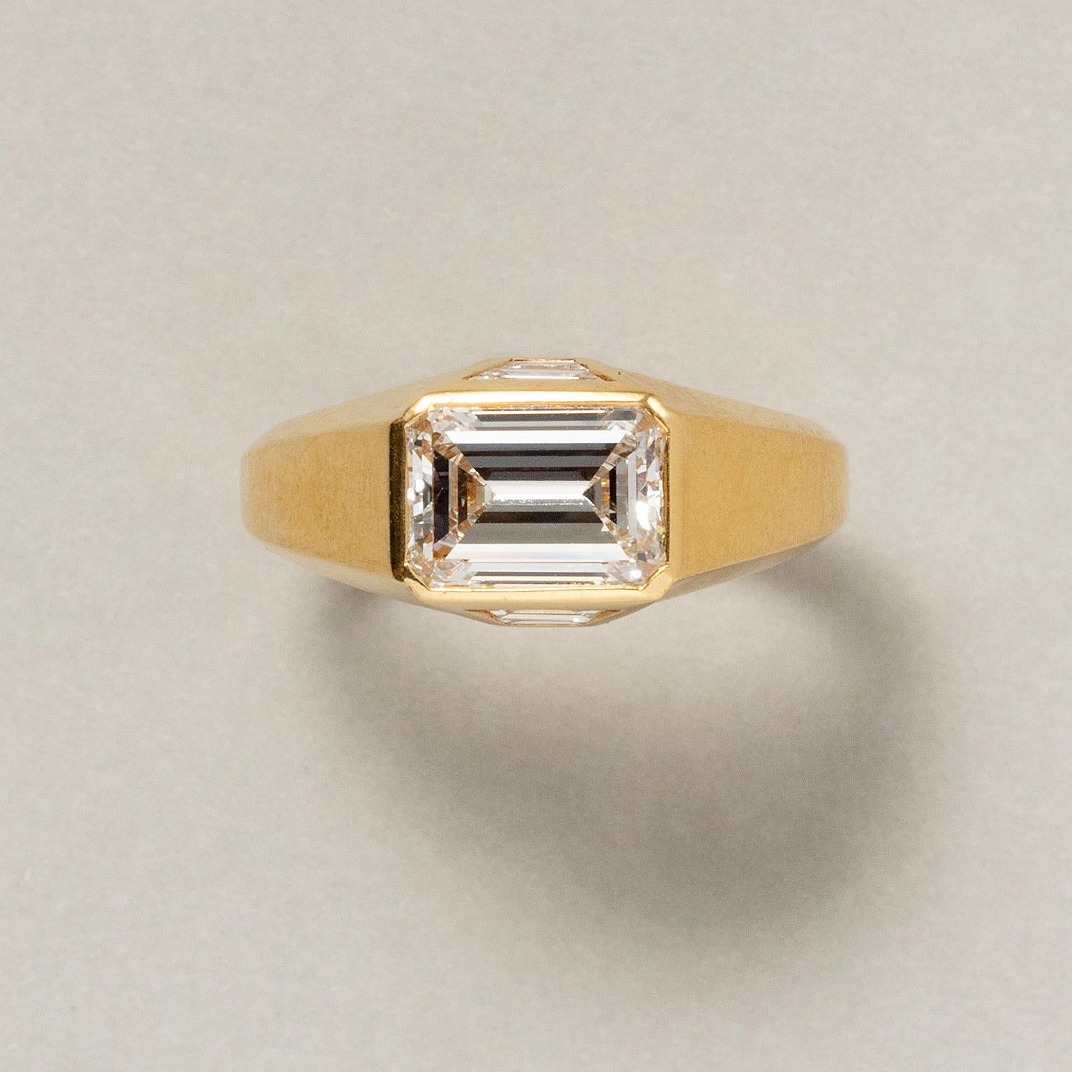 Ein Single Stone Ring aus 18 Karat Gold, besetzt mit einem Diamanten im Stufenschliff und je einem Dreieck mit zwei Diamanten im Trapezschliff (insgesamt 1,77 ct, F - Vvs), signiert: Bulgari, Rom.

Ringgröße: 17,25 mm / 6 3/4 US
Gewicht: 7,17 Gramm