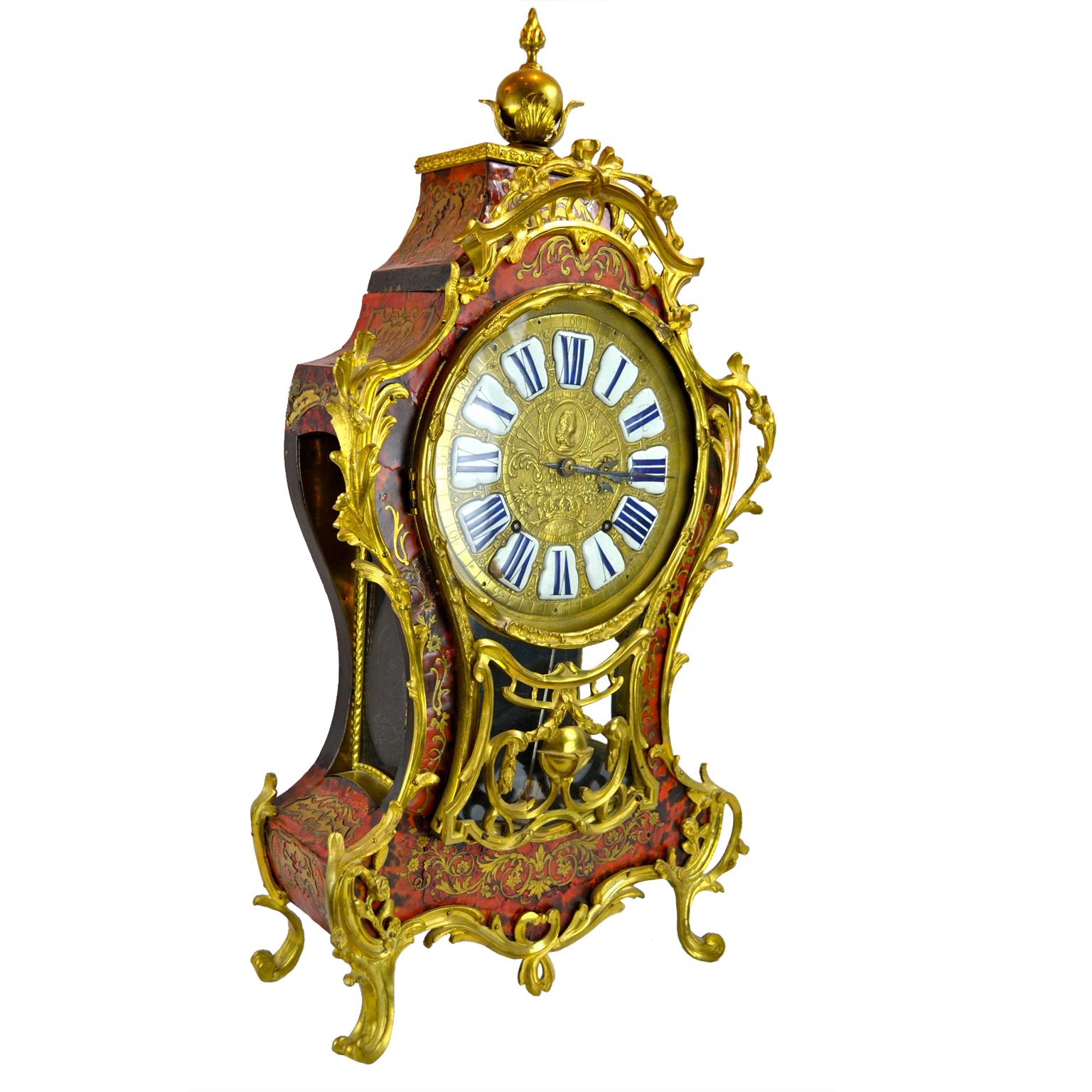 Eine Boulle-Manteluhr aus der Zeit von Louis XV  Das Gehäuse ist mit Messing eingelegt und mit Rokoko-Rankenwerk und vergoldeten Bronzebeschlägen verziert.  Der abnehmbare, abgeschrägte Deckel des Gehäuses ist mit einer vergoldeten Kugel und einer
