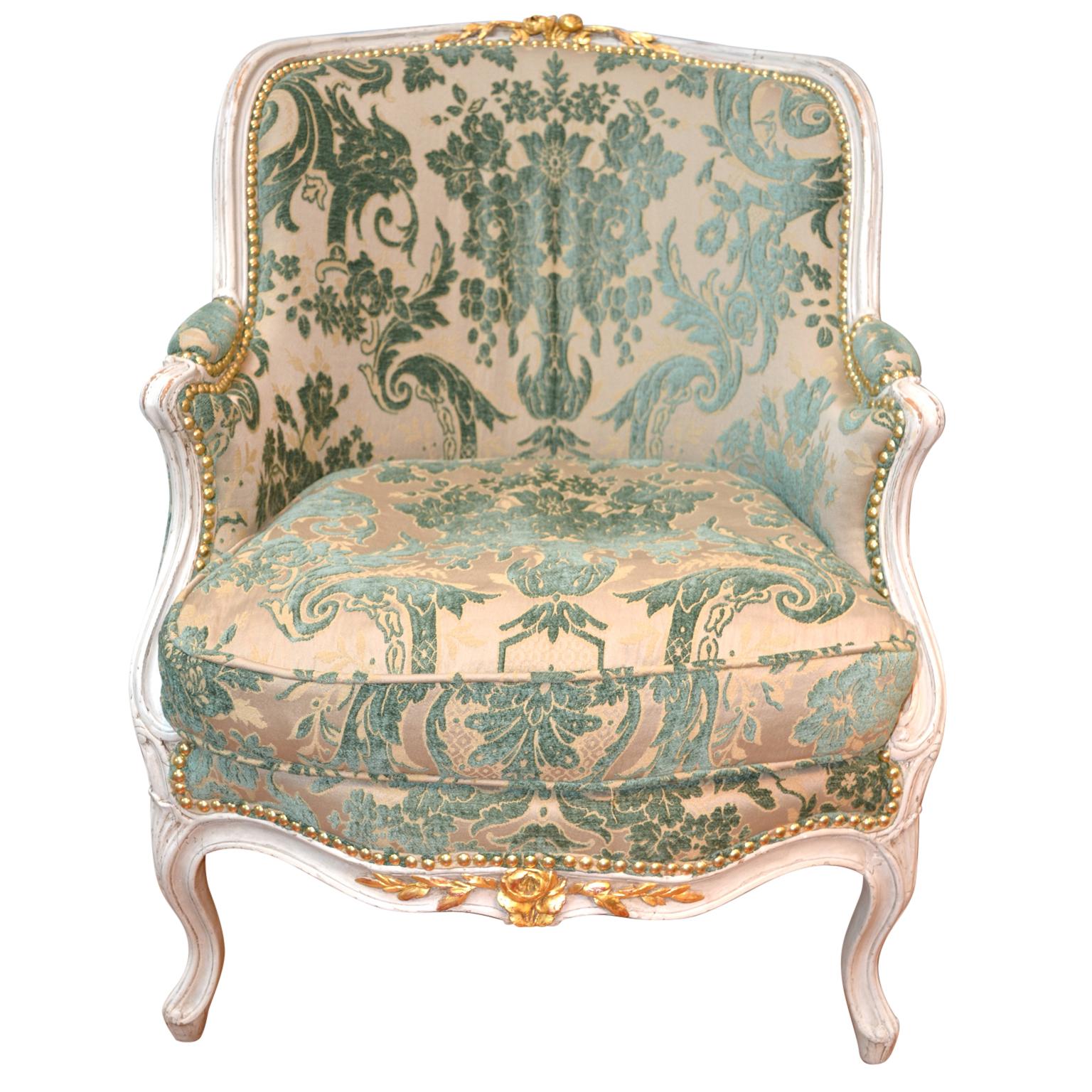 A period 18th century Louis XV upholstered armchair, the painted frame with water gilt highlights to the carved roses and leafs on the back rail and lower front. The chair is similar to chairs made by Gourdin who was one of the most important