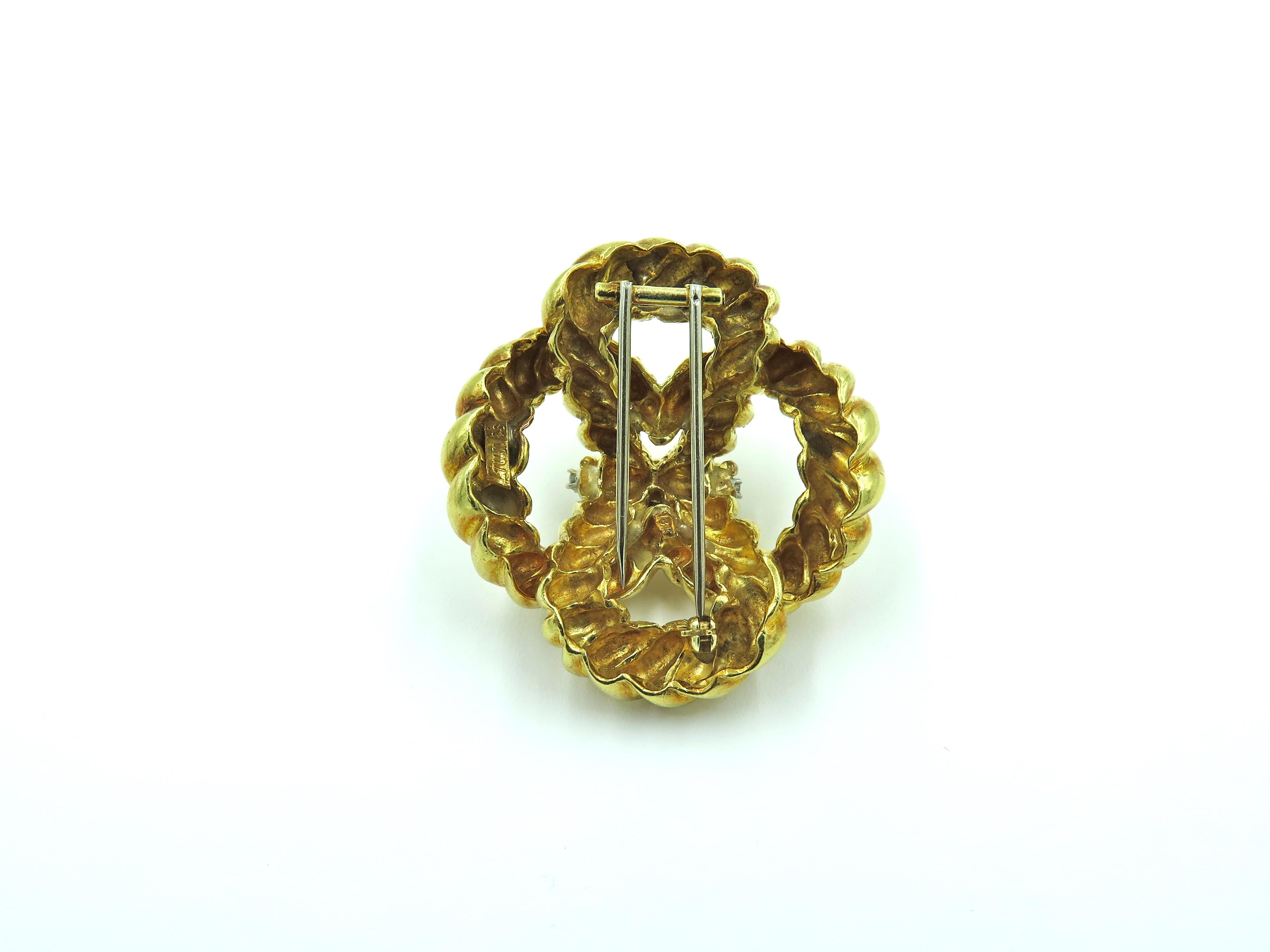 An 18 karat yellow gold and diamond brooch. Circa 1960. Designed as a polished ropework knot, enhanced by a line of circular cut diamonds. Seven (7) diamonds weigh approximately 0.30 carat. Length is approximately 1 3/4 inches, gross weight is