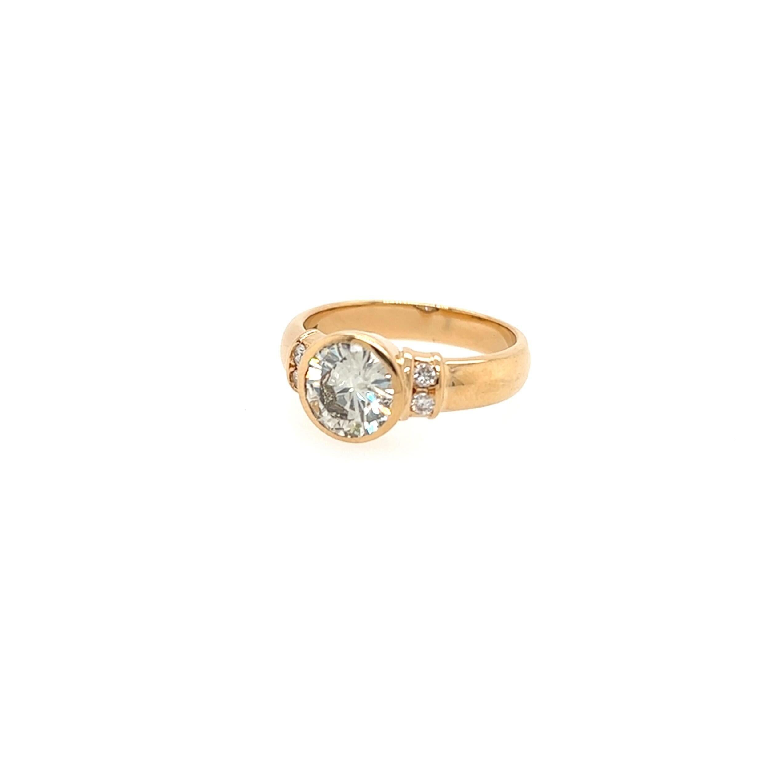 An 18 karat yellow gold and diamond ring.  Centering a bezel set brilliant cut diamond flanked by two (2) brilliant cut diamonds on each side.  Total diamond weight approximately 1.15 carats.  Color:  L-M.  Clarity: SI2.  Size approximately 4 1/4. 