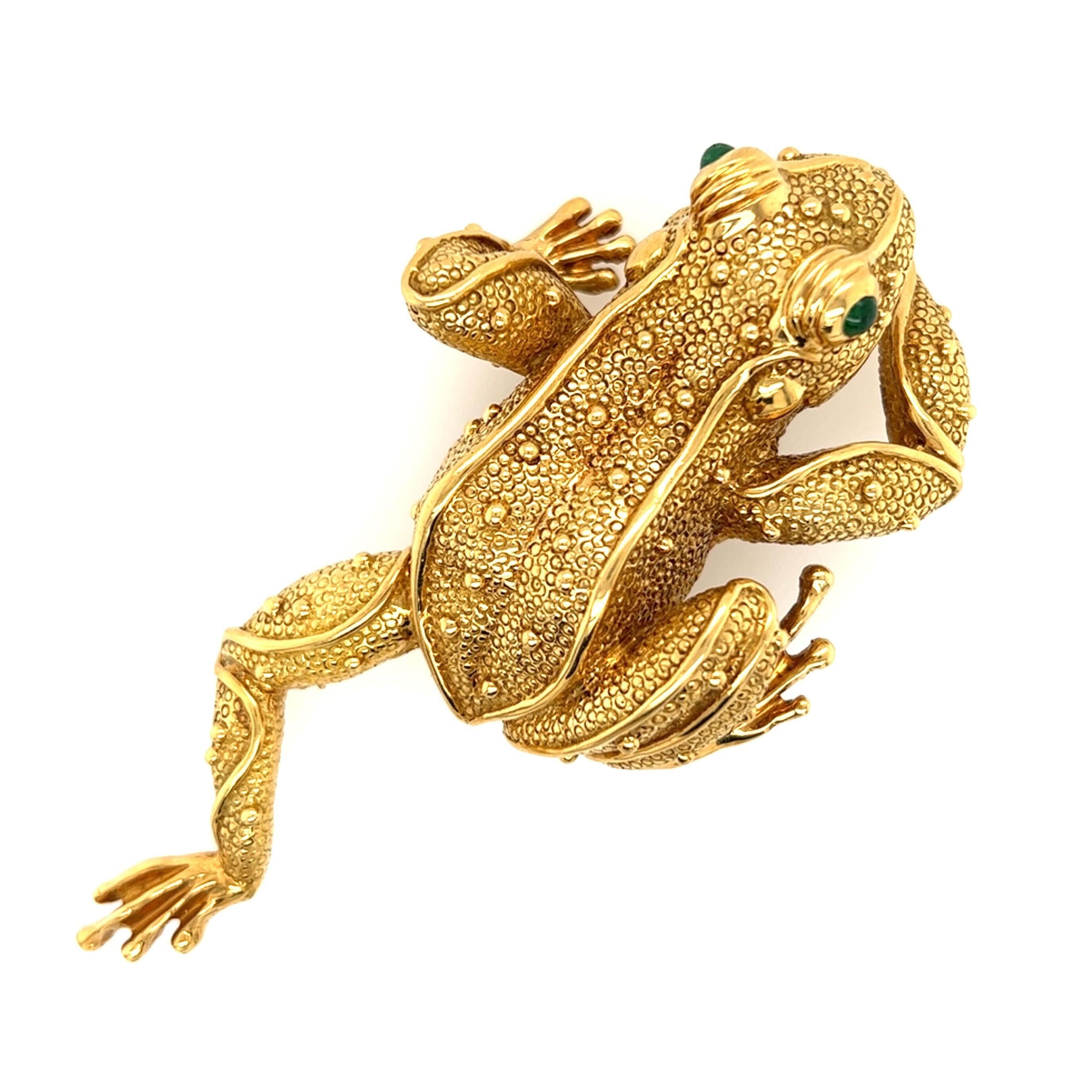 An 18 karat yellow gold frog brooch, with cabochon emerald eyes. Length is approximately 4 inches, gross weight is approximately 88.0 grams. 