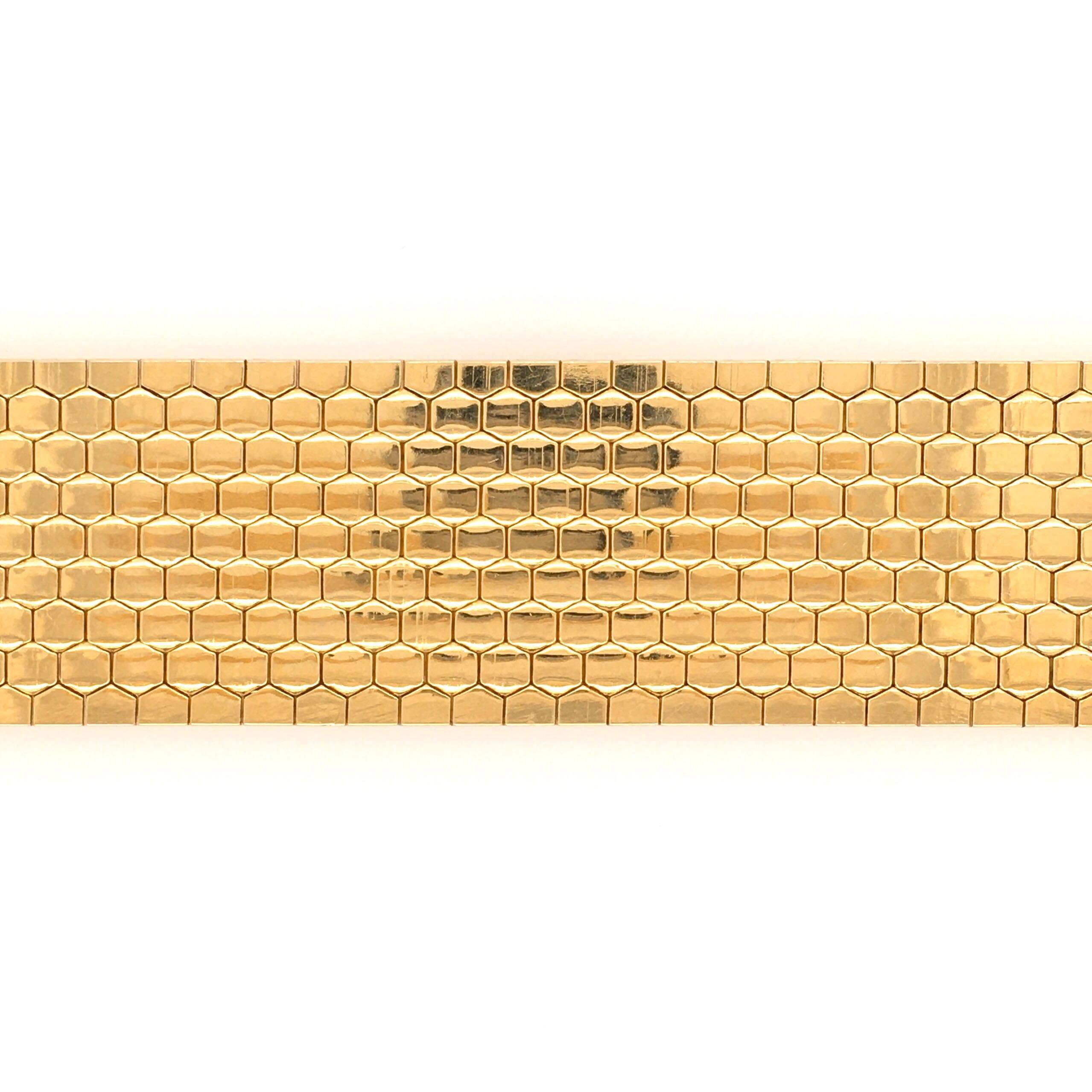 An 18 karat yellow gold bracelet. Italy. Designed as a matte gold wide flexible band with hexagonal shaped pattern. Width is approximately 1 1/16 inches, length is approximately 7 3/4 inches, gross weight is approximately 60.3 grams. Stamped Made in