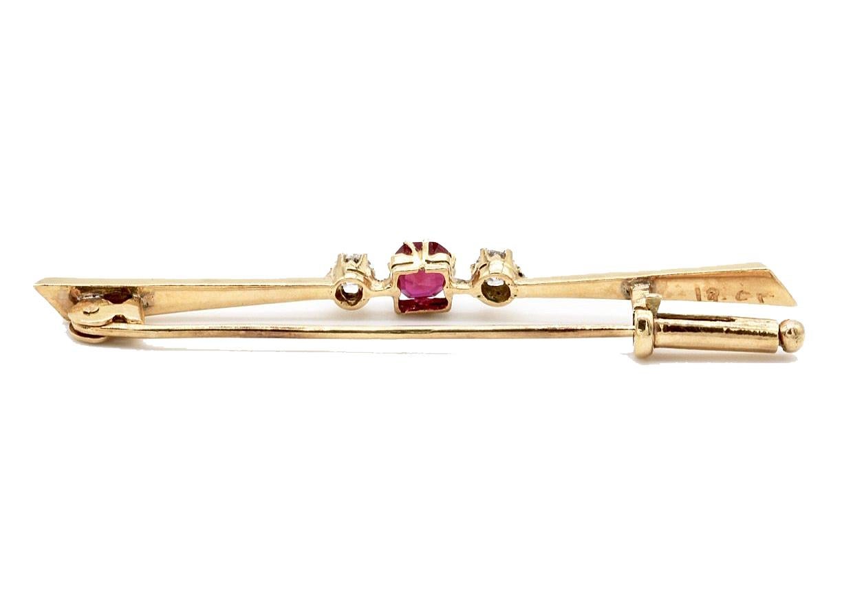 An 18 Kt Yellow Gold Diamond & Ruby tie pin. The central ruby flanked by two diamonds.
Stamped 18 Kt.
Total diamond weight approximately 0.14 Ct.
With a trombone fixing.