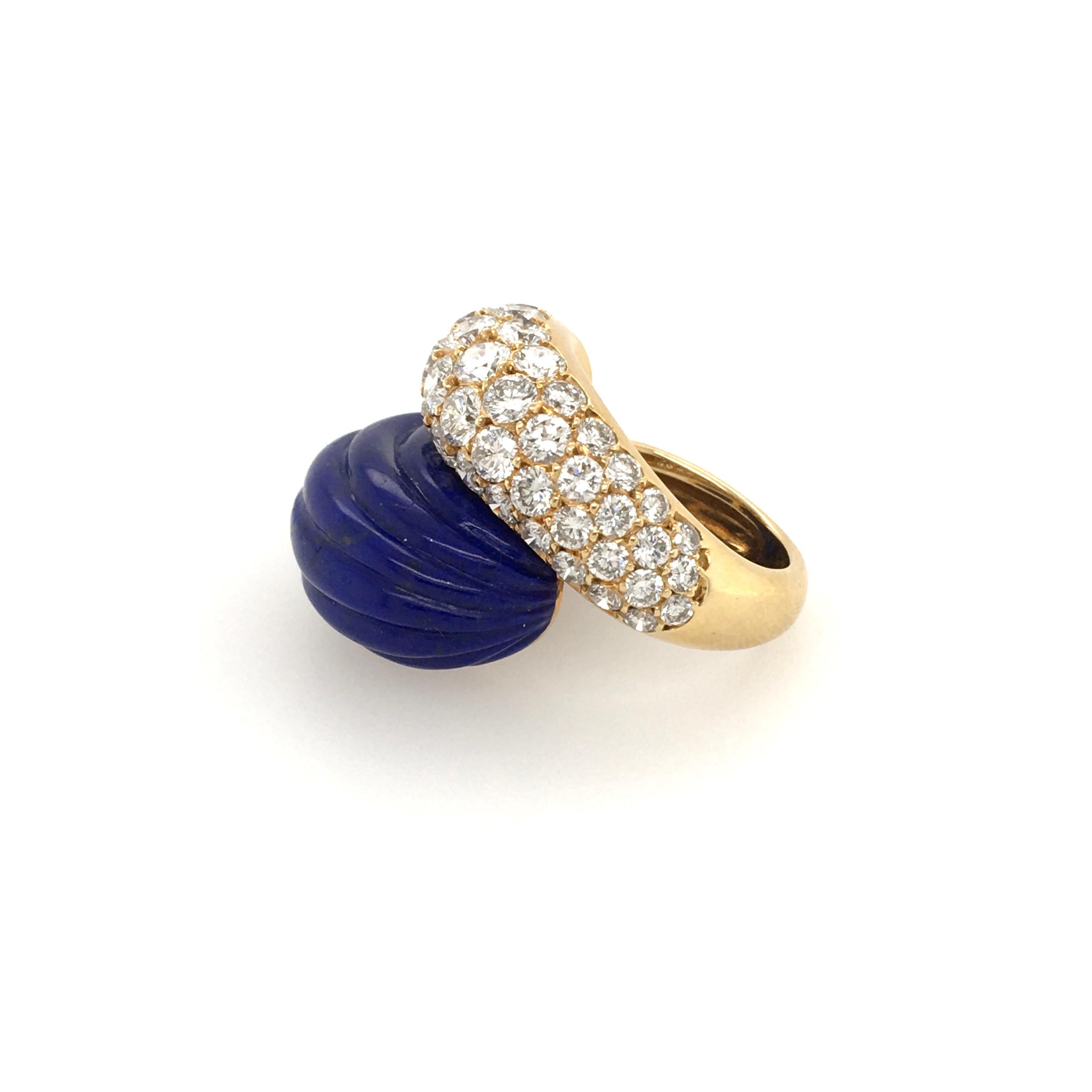 An 18 karat yellow gold, fluted lapis lazuli and diamond ring.  French. Circa 1960. Of bypass design, set with a pave set diamond bombe drop shaped plaque and a carved lapis lazuli plaque. Forty four diamonds weigh approximately 3.50 carats. Size 5