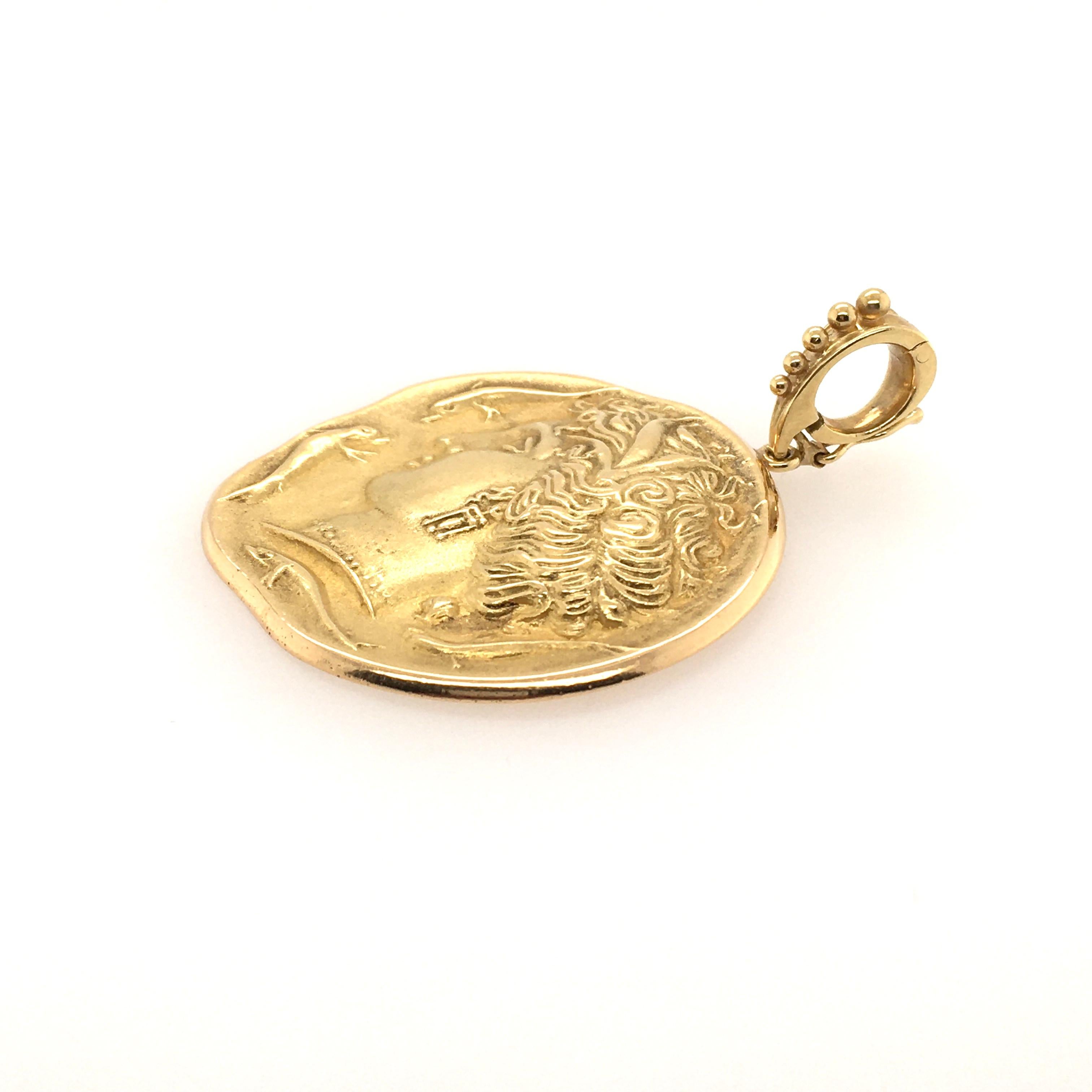 An 18 karat yellow gold pendant. Designed as a disc, depicting the goddess Amphitrite, enhanced by dolphins motifs, from a bale enhanced by beadwork. Length is approximately 2 inches (including bale), gross weight is approximately 18.5 grams.