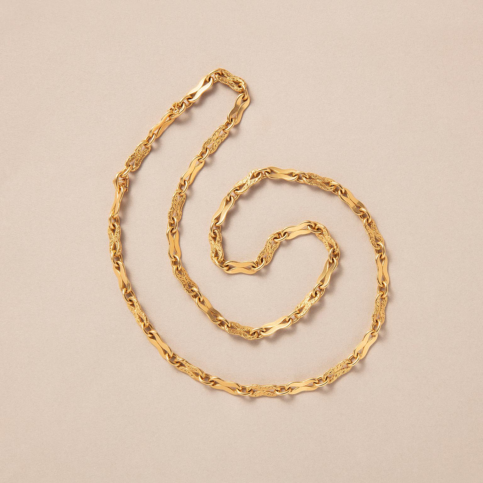 Une longue chaîne en or 18 carats avec huit maillons tressés en forme alternés avec des maillons polis en forme de huit reliés à des maillons ovales avec une marque de maître usée, très probablement Georges Lenfant et des marques d'essai françaises