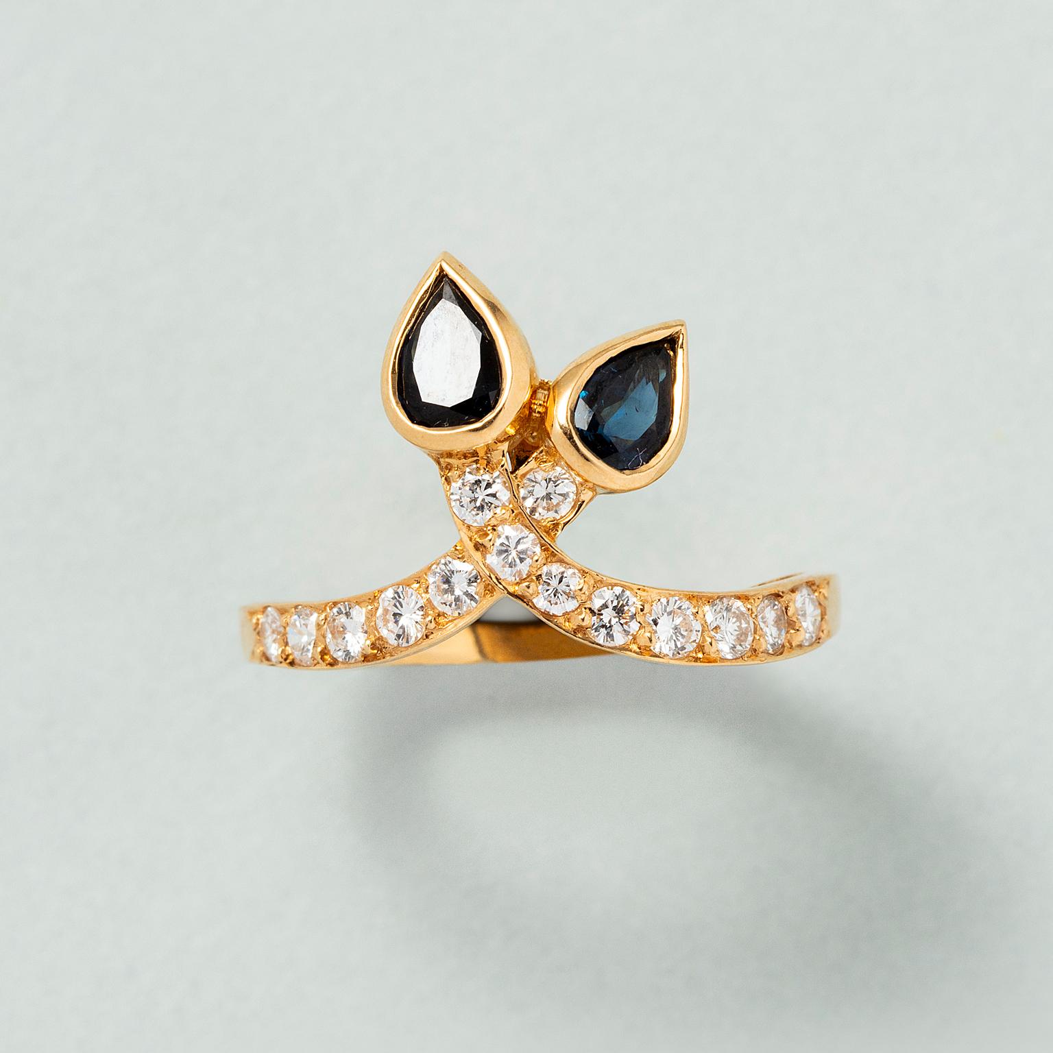 Anello in oro 18 ct. con due fasce incastonate di diamanti che si incrociano con due zaffiri taglio pera ad ogni estremità, Francia. 

peso: 3,8 g 
altezza: 12 cm 
misura dell'anello: 16,5 / 6 US / 52