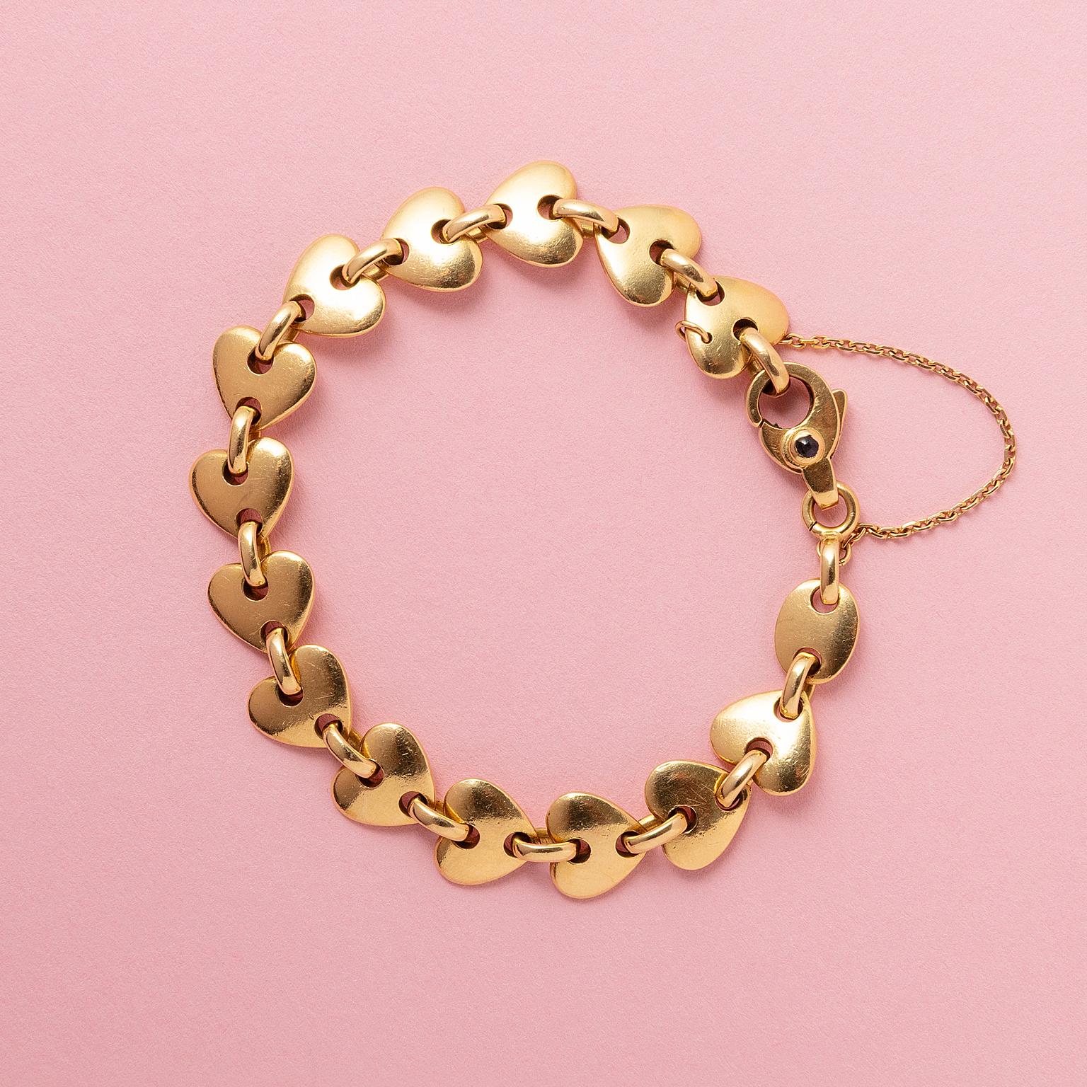 An 18 carat yellow gold bracelet with heart shaped links and with a large lobster clasp on which a cabochon cut sapphire, and a safety chain, signed: Julian Cannes, France, circa 1980.

weight: 30.1 g
length: 19 cm fits a 15 - 17.5 cm wrist
width: