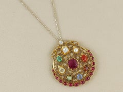 An 18K gold Navratna pendant set with nine natural gemstones with diamond