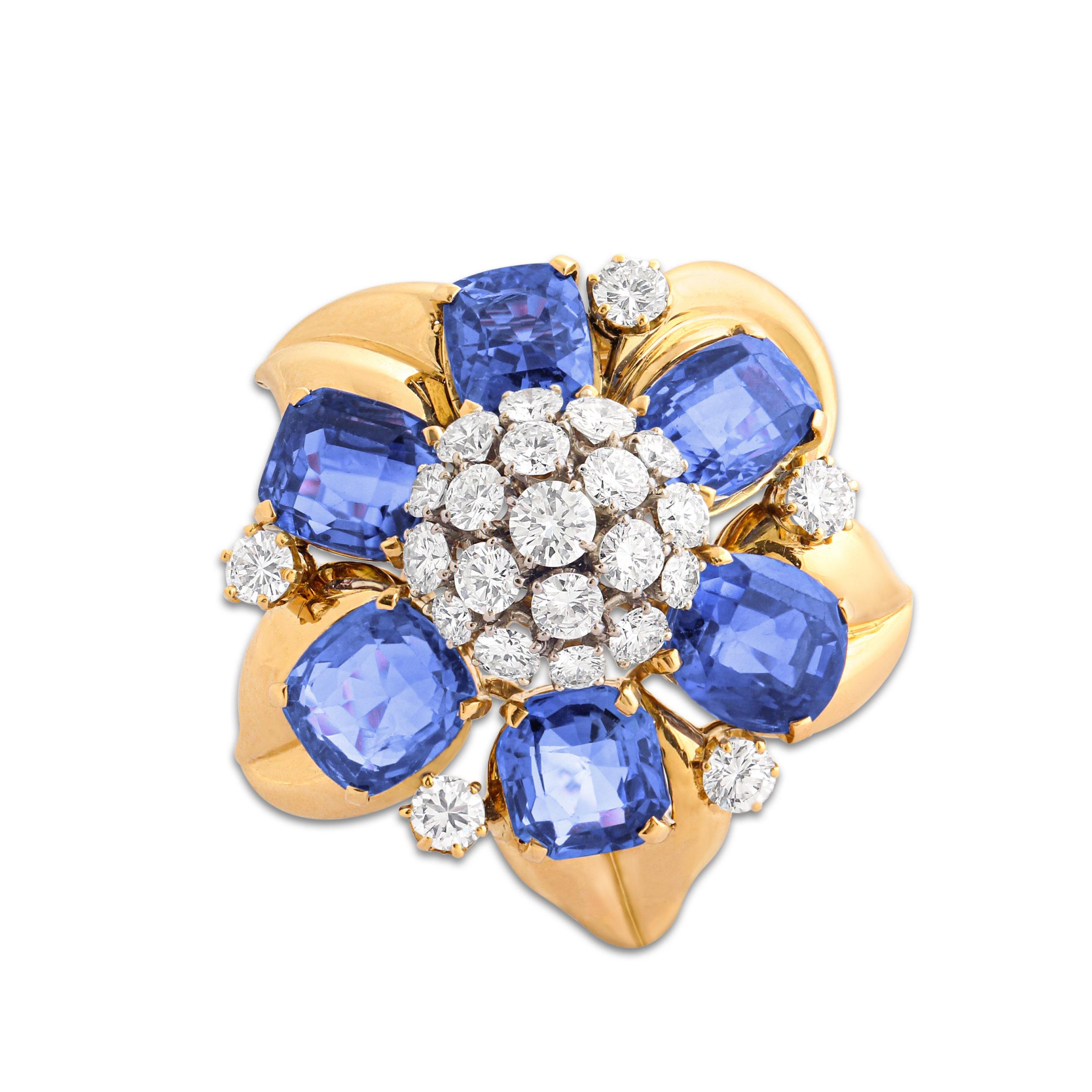 An 18k gold, sapphire and diamond flower brooch by Bulgari. Set with six cushion-cut sapphires around a cluster of round-cut diamonds. Total sapphire weight = 16 carats, total diamond weight = 2.50 carats