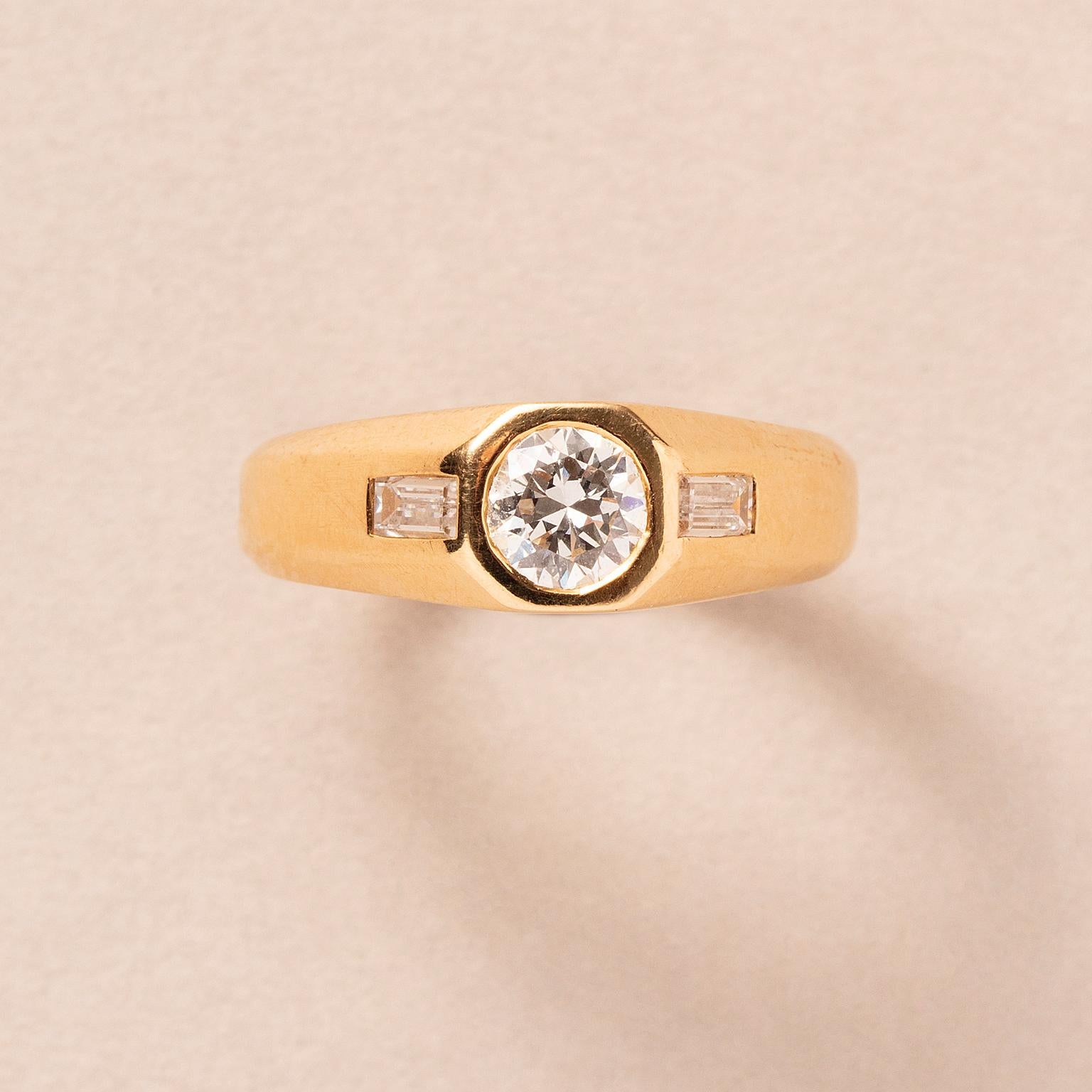 Anillo de oro de 18 quilates engastado con un diamante talla brillante (aprox. 0,75 quilates, F-G, Vs1) con un diamante talla baguette a cada lado, firmado: Bulgari.

peso: 6,25 g
Talla: 17,25 mm / 7 US
anchura: 2,8 - 7 mm