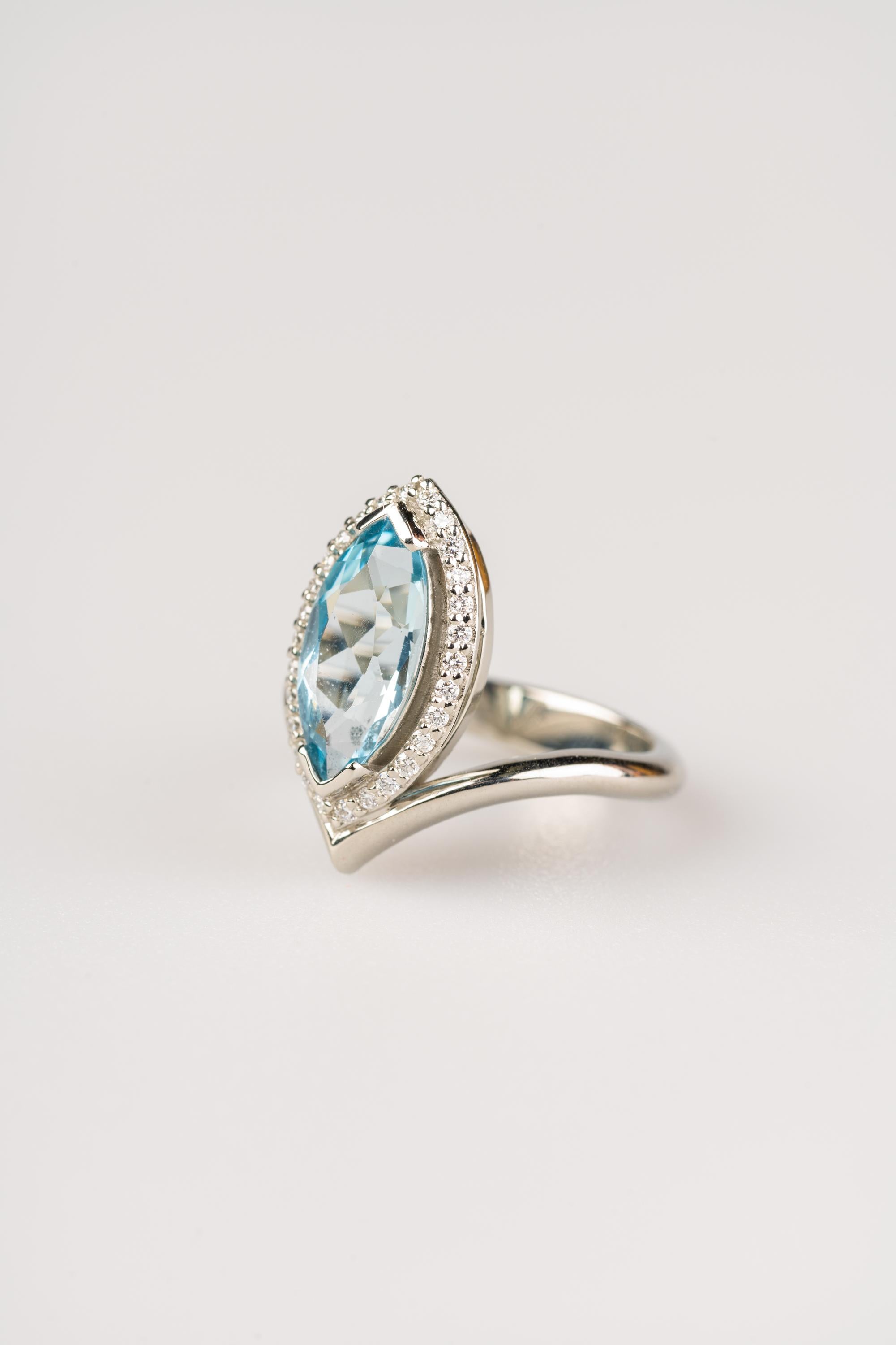 An 18k white gold ring set with one 2.29 carat marquise shaped aquamarine, and a halo of (28) 1.2mm white round diamonds, F color VS clarity (.18 carats). Ring size 7.  This ring was made and designed by llyn strong.
