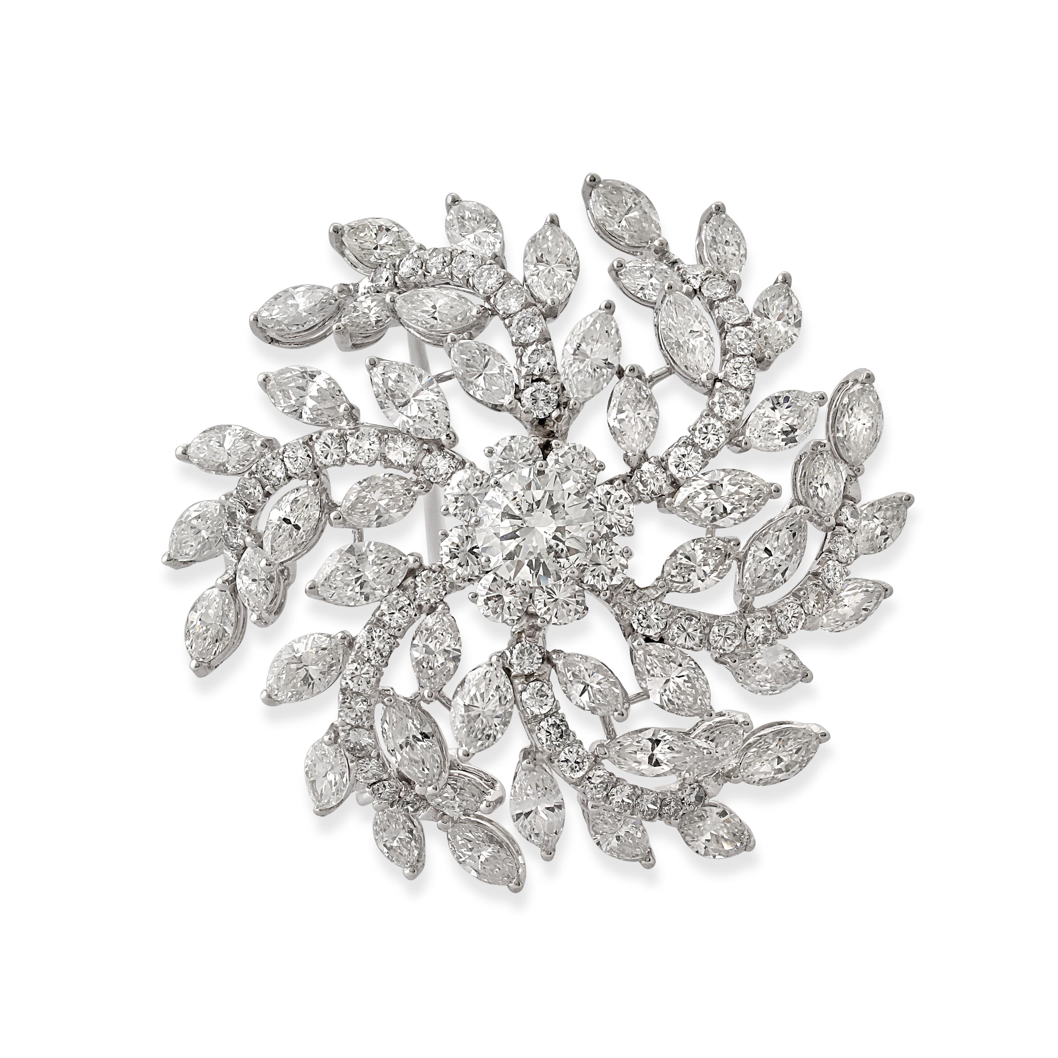 An 18k white gold and diamond floral brooch. Designed as swirled flowering branches that resemble a catherine wheel. Set at the centre with a circle-cut diamond with marquise-cut diamonds as leaves on the branches.