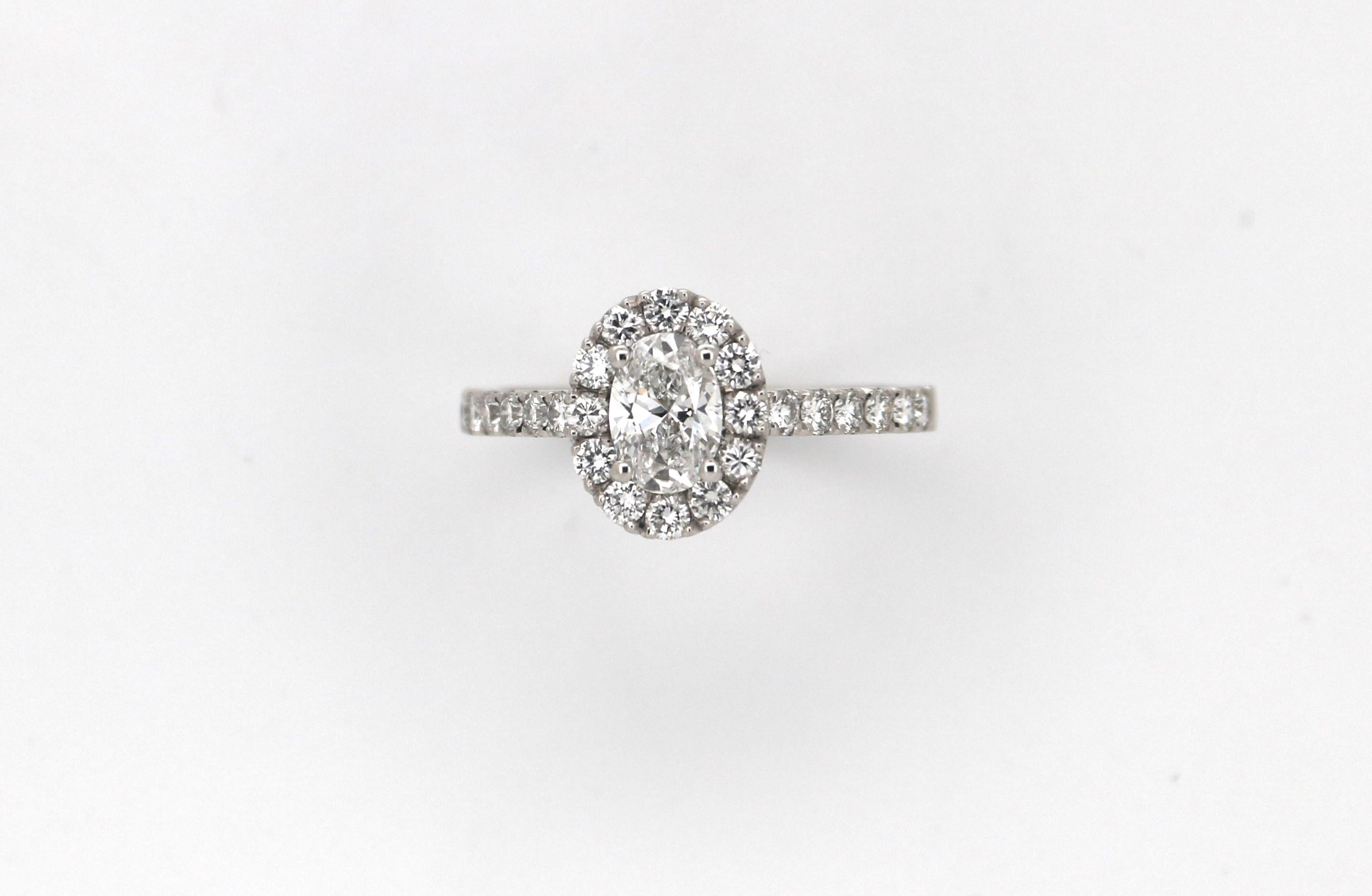Un anello a grappolo / entourage in oro bianco 18k, unico e fatto a mano, con al centro un diamante naturale taglio ovale del peso di 0,65ct, accompagnato da un certificato di laboratorio GIA che attesta che il colore del diamante è E e la purezza