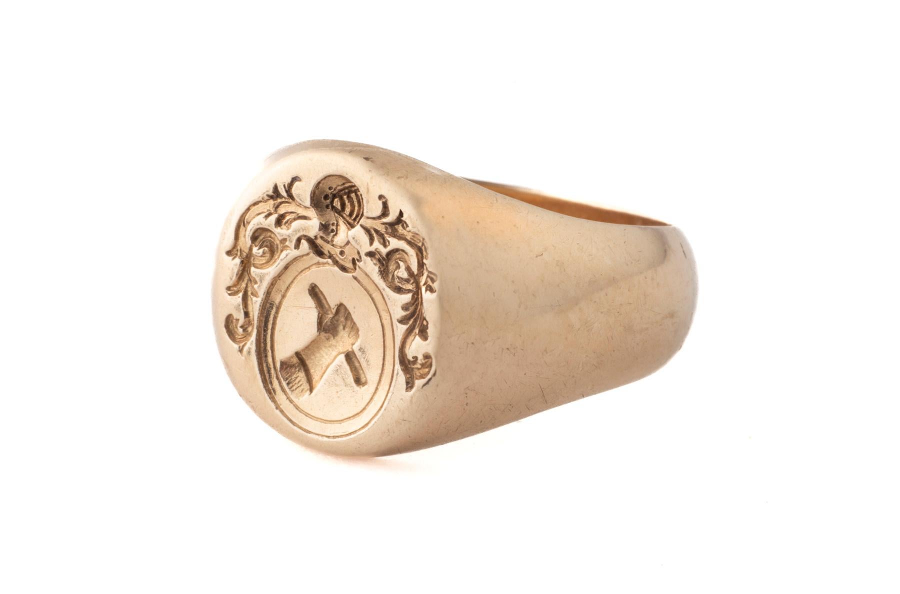 Un anello con sigillo francese vittoriano a 15 Kt che mostra tutti i segni del potere. C'è un braccio alzato che mostra un pugnale. Questo simbolo indica la volontà di prevalere. Sopra il braccio c'è un elmetto da guerriero con protezione per il