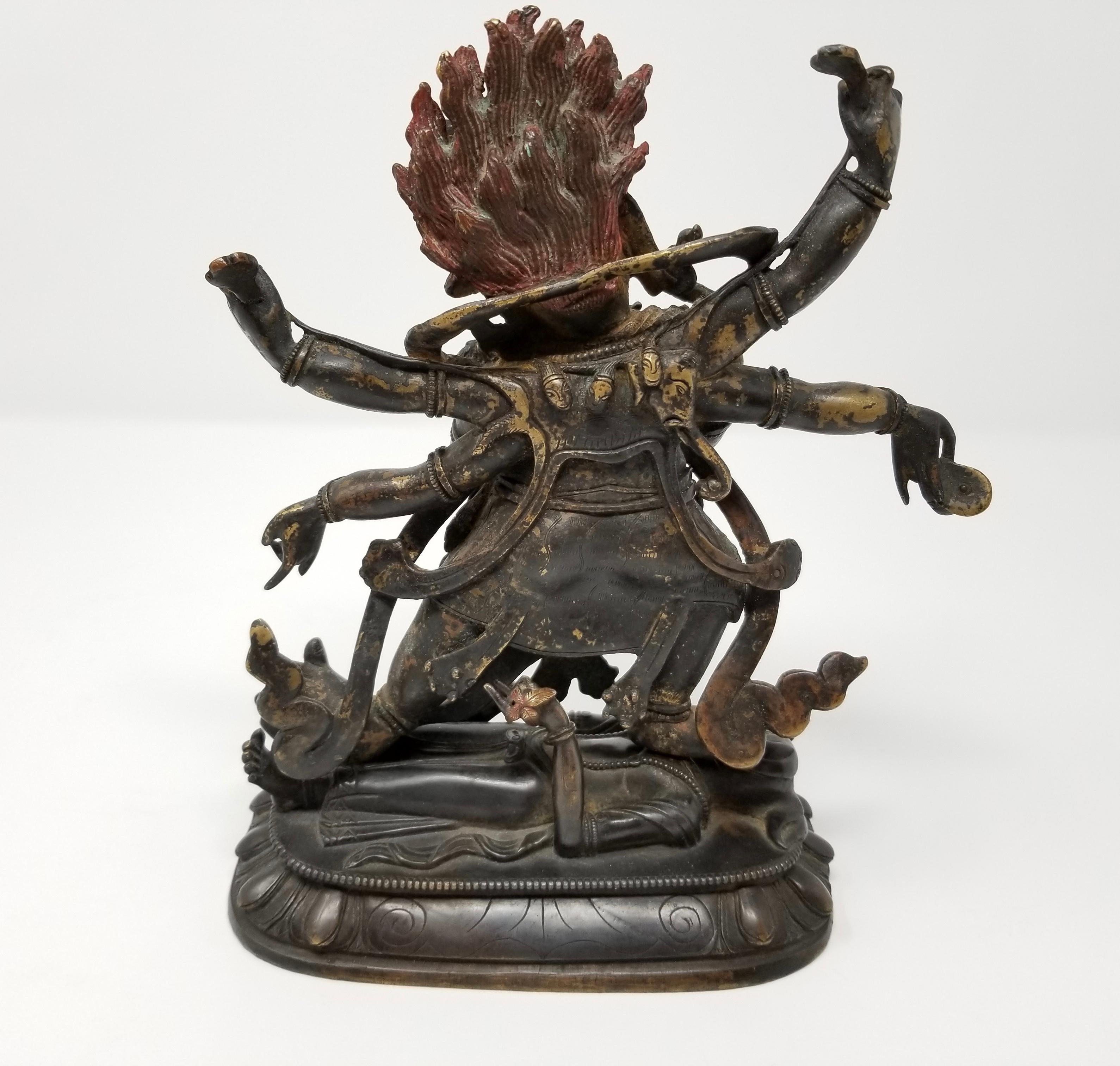 A well cast mid to late 19th century Tibetan polychrome lacquered bronze figure of the 6-armed Mahakala Deity. The diety is seen standing atop an elephant-headed deity portrayed sleeping on an oval lotus base. The deity is seen wearing jewelry,