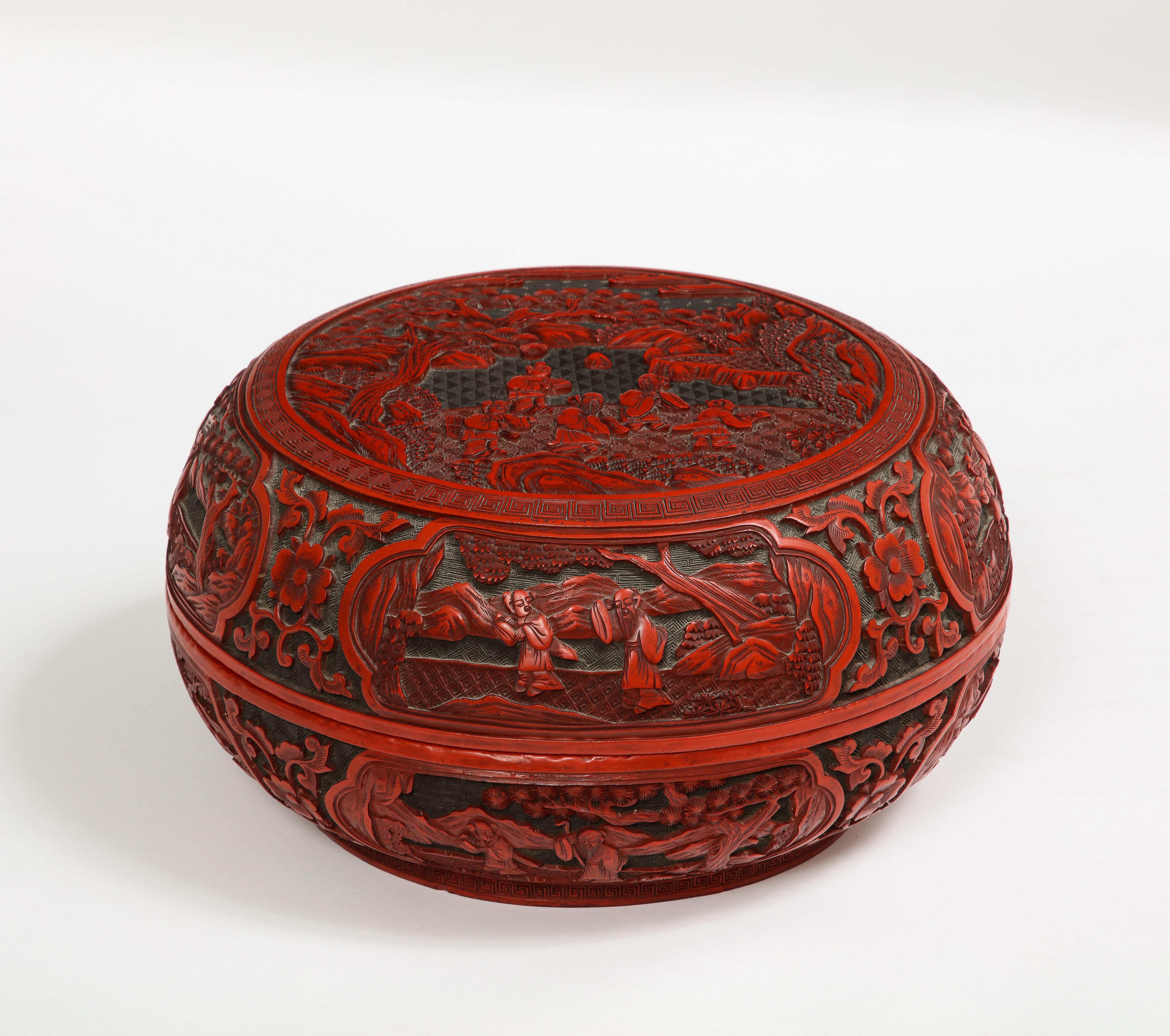 Une boîte circulaire chinoise en cinabre du 18e/19e siècle avec de multiples cartouches de familles. C'est une pièce merveilleuse avec des détails très fins sur le panneau supérieur principal de la boîte. Le panneau supérieur est magnifiquement