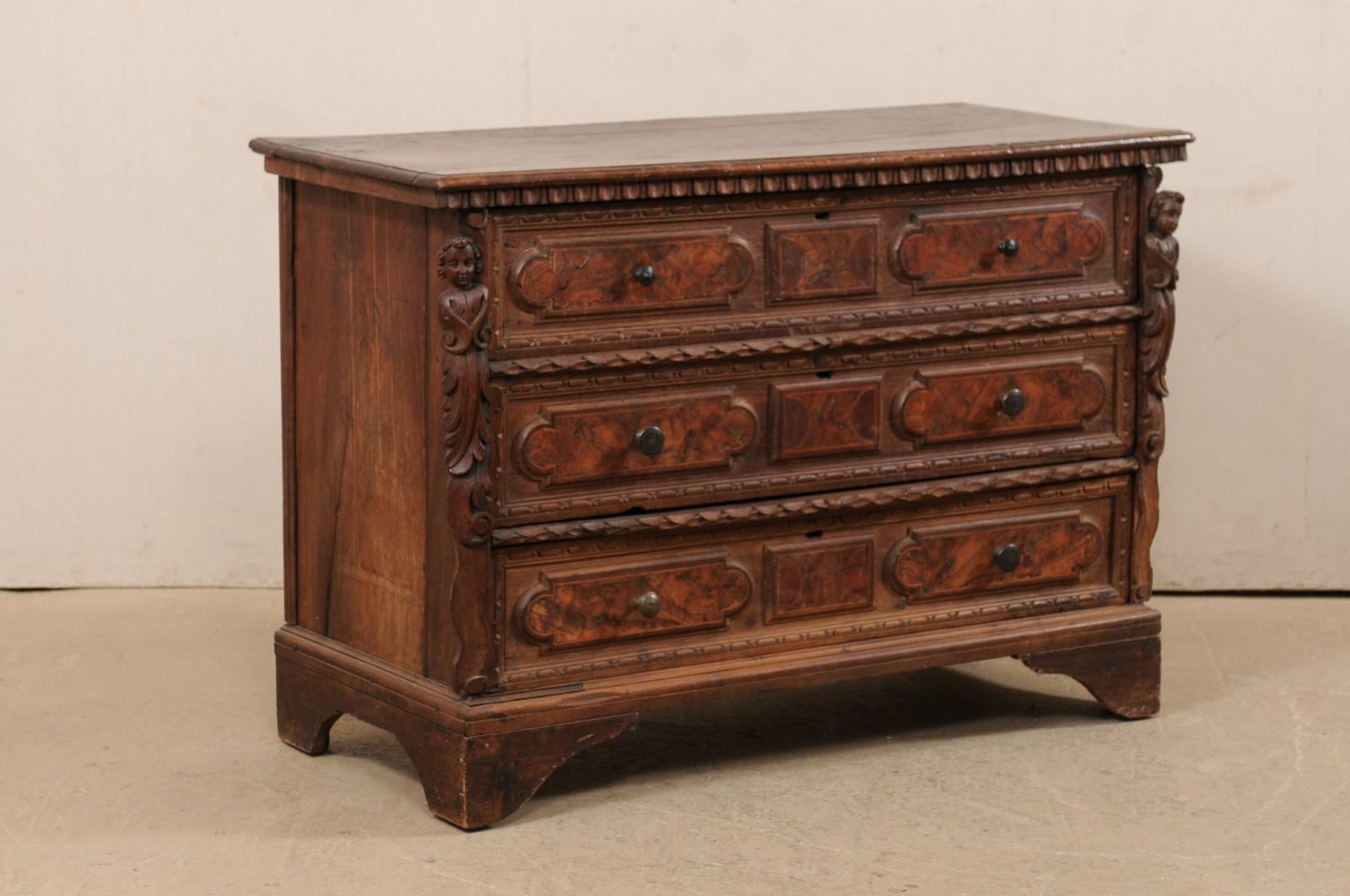An Italian carved wood chest adorn with putti accents from the 18th century. This antique cassettiera (chest of drawers) from Italy features an egg-and-dart carved trim at the underside of the top edge, and a pair of side posts which are beautifully