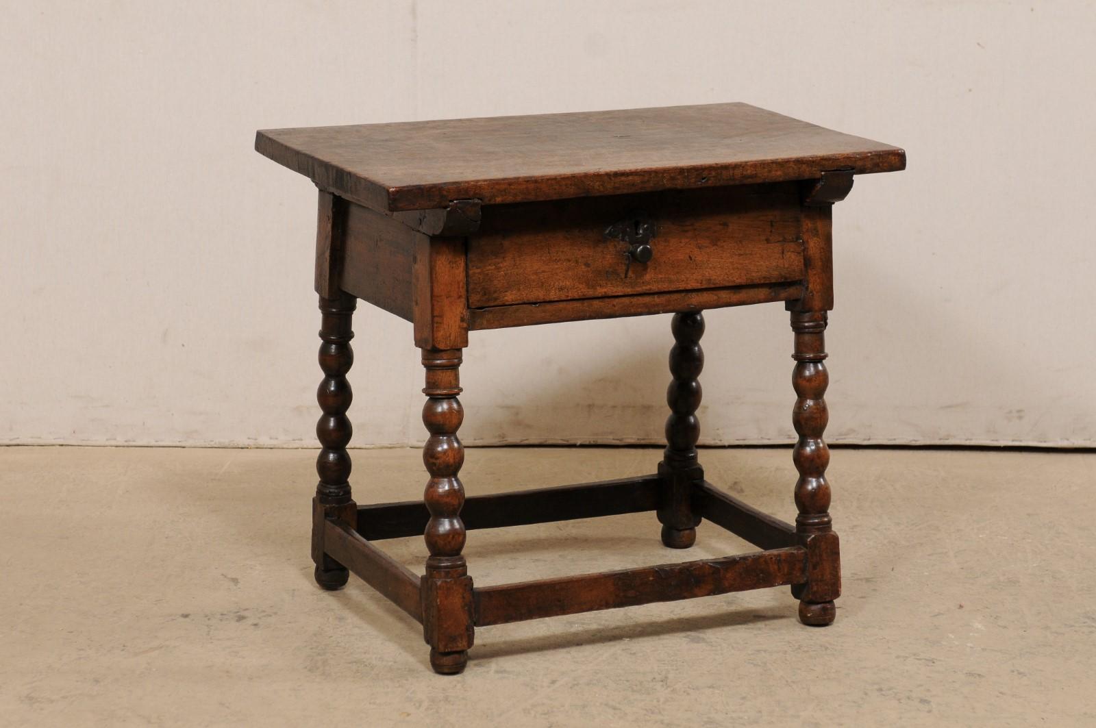 An Italian occasional table with single drawer, from the 18th century. This antique table from Italy has a rectangular-shaped top, which overhangs the apron below which houses a single drawer at one side. The table is raised on four ball-turned and