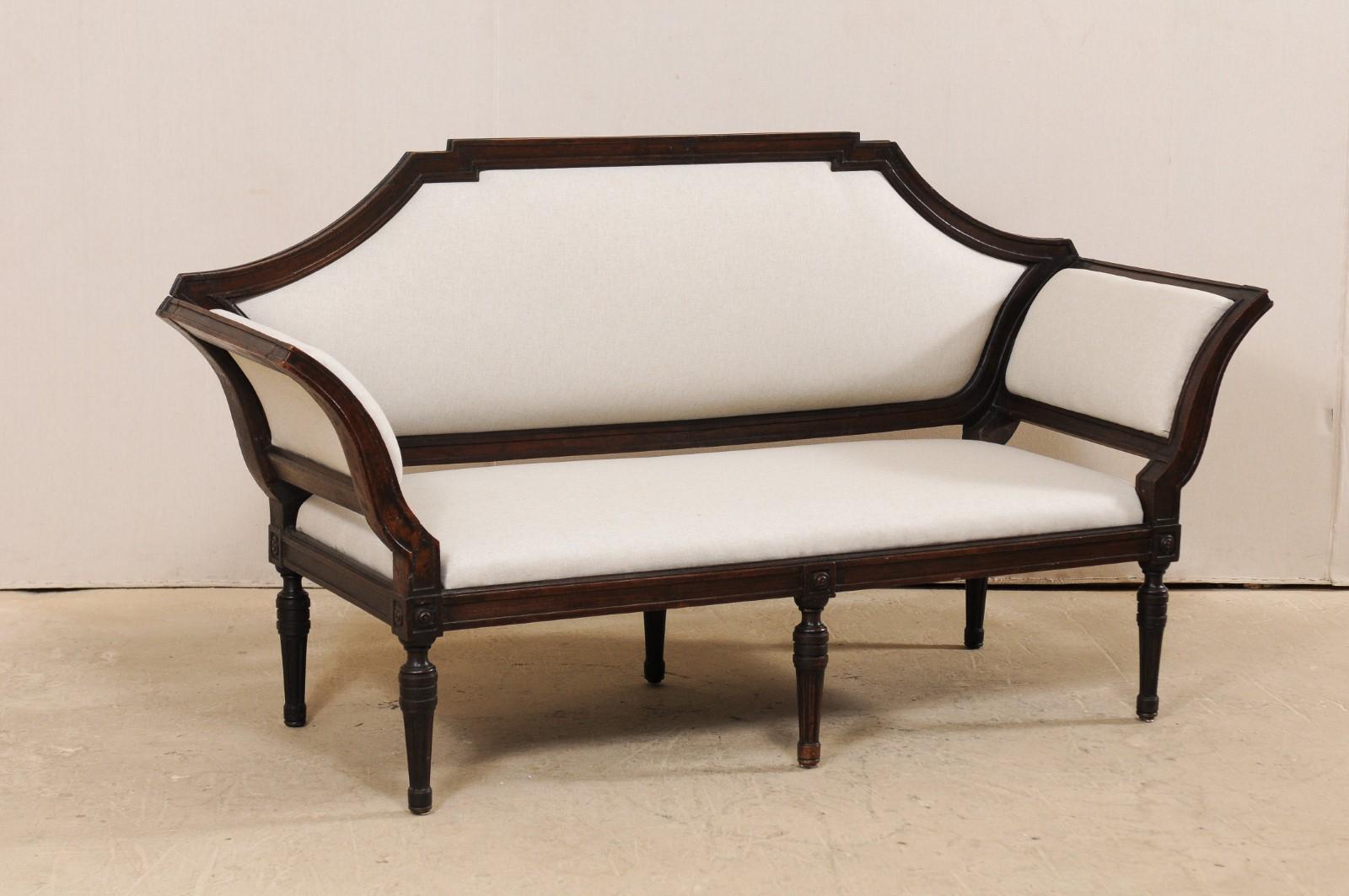 An 18th century Italian Venetian sofa with removable back. This antique sofa from Italy, just over 6 feet in length, features a beautiful wood trimmed lines throughout; the flat-edged wooden crest rail which flows gently down the arms, which