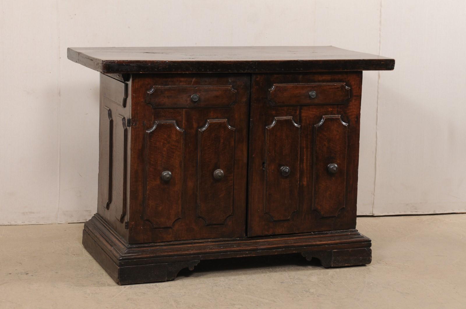 An Italian two-door walnut wood cabinet from the 18th century. This antique buffet from Italy, created from beautiful walnut wood, has a thick 2.25 inch top, is decorated about the front and each side with raised panels, and is raised upon a flat
