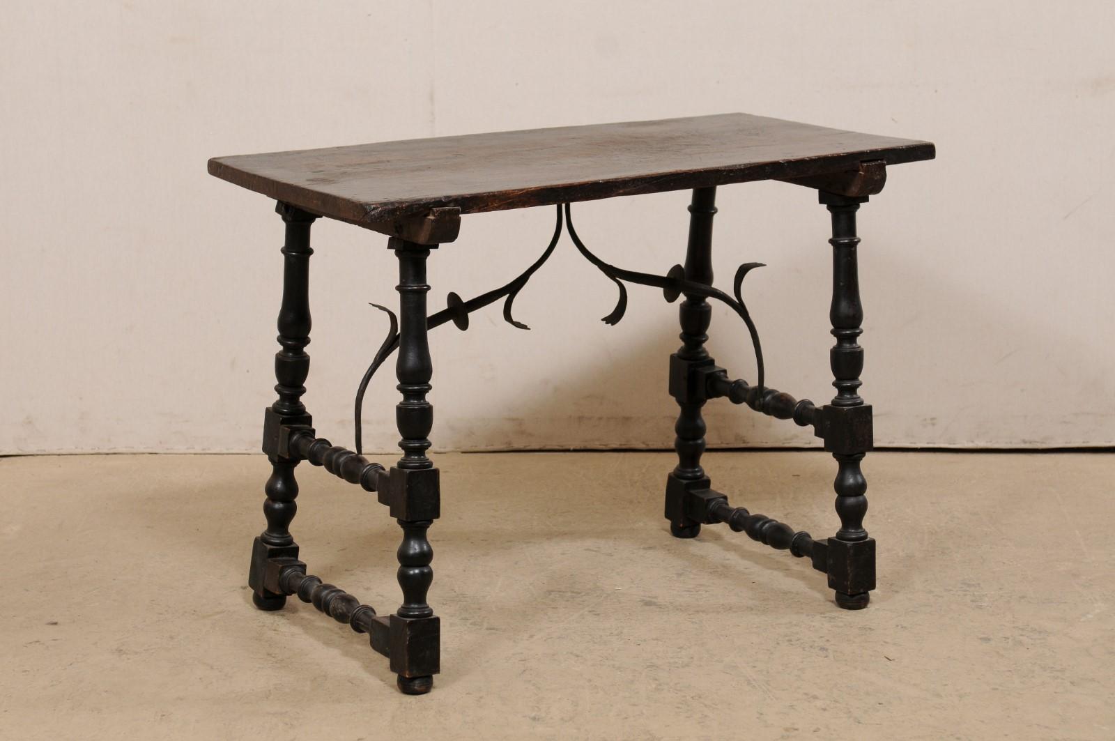 An Italian wood trestle-leg table, with decorative forged-iron stretcher, from the 18th century. This antique table from Italy features a rectangular-shaped top, which is raised upon a pair of nicely-turned, trestle-styled legs (with a pair of