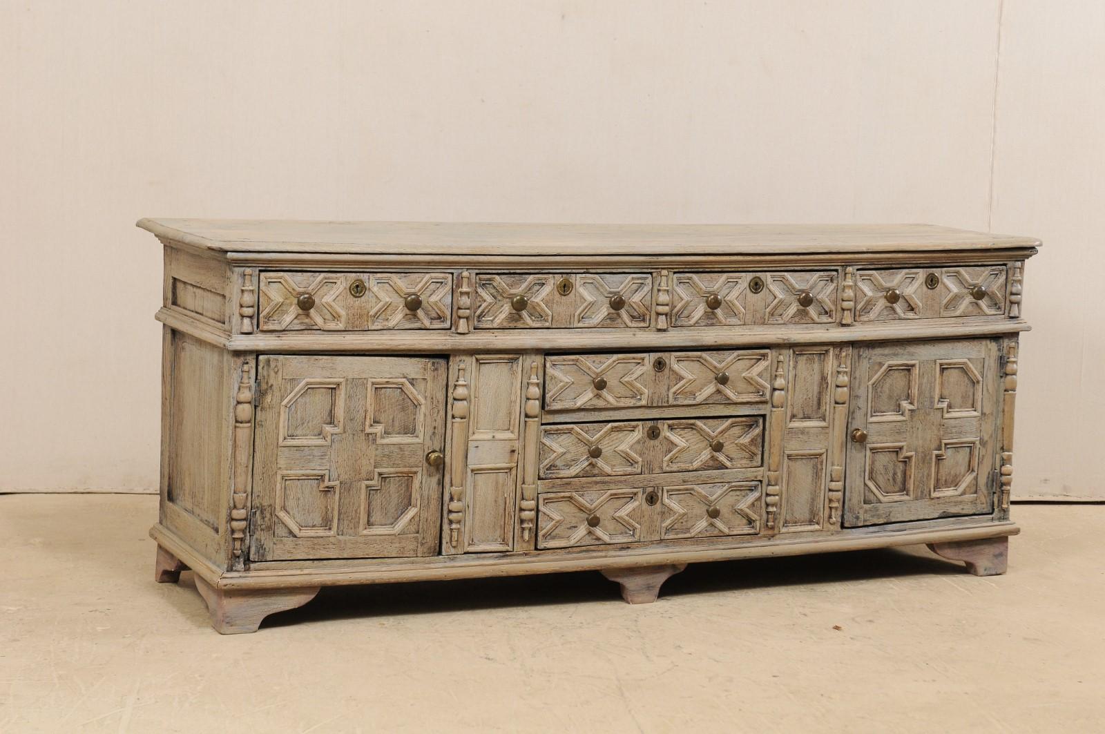 An English console cabinet, with nicely trimmed front, from the 18th century. This antique chest from England features a long rectangular-shaped top over a case which houses four horizontally set drawers above three larger drawers set at lower