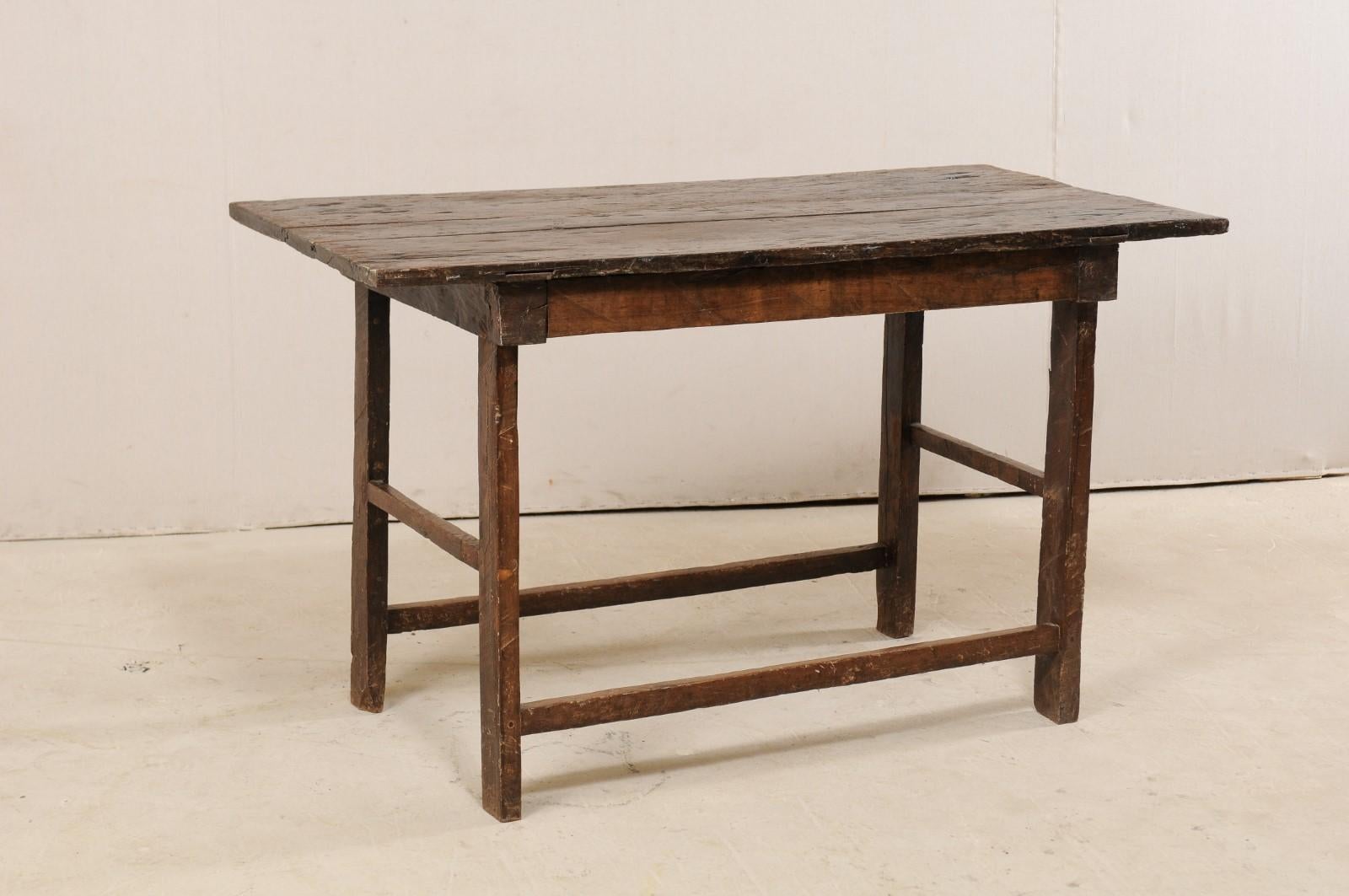 An 18th century table of peroba wood from Brazil. This antique Brazilian occasional table has a simple, bucolic design with a rectangular plank board top which overhangs the simple apron on which it rests. The table, which is nearly counter height