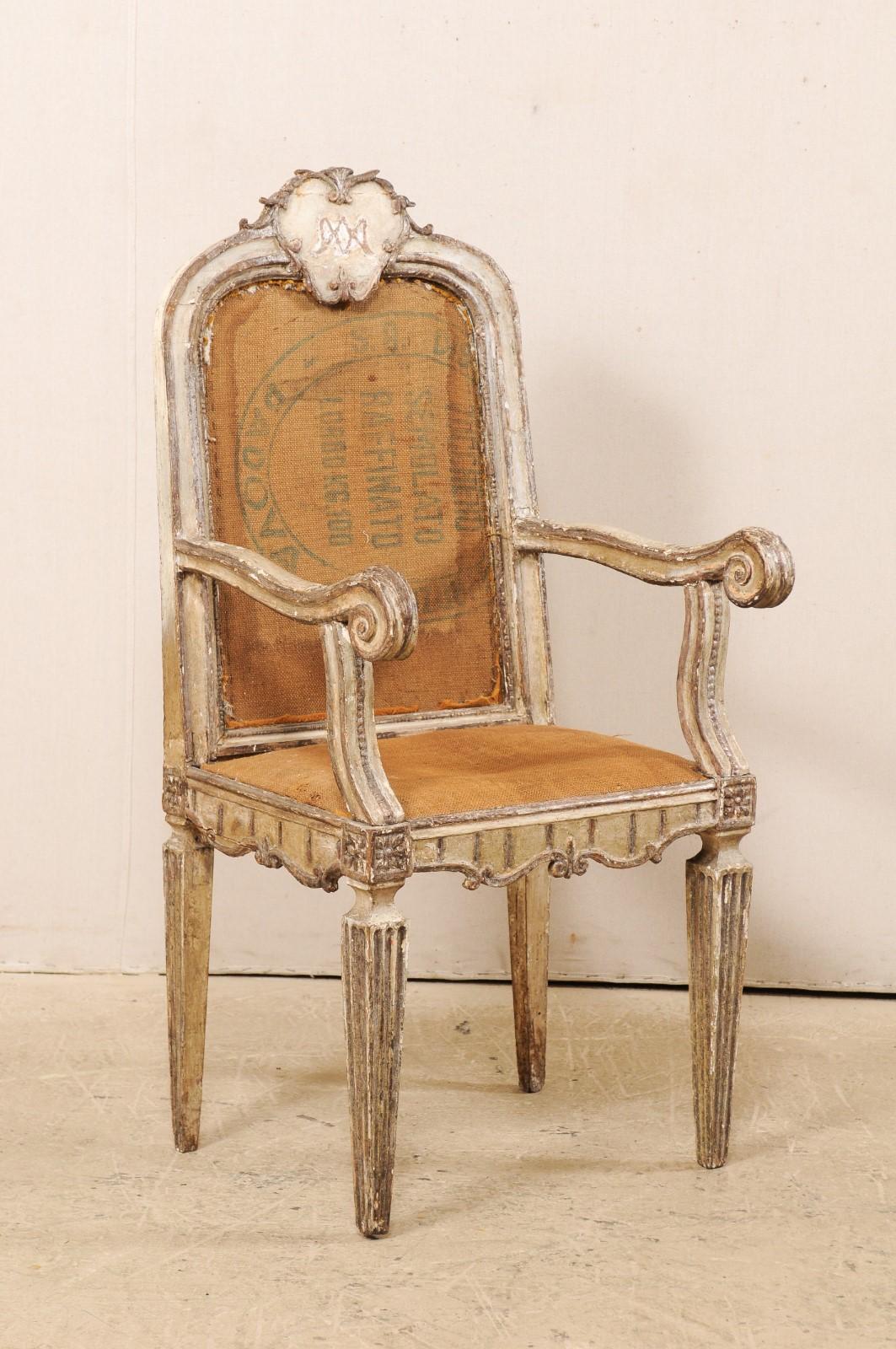 A single Italian carved-wood accent armchair from the 18th century. This antique chair from Italy has a nicely carved stylized plaque adorning its back rail crest. Gently curved arms terminate into scrolled knuckles. The seat and arch-shaped back