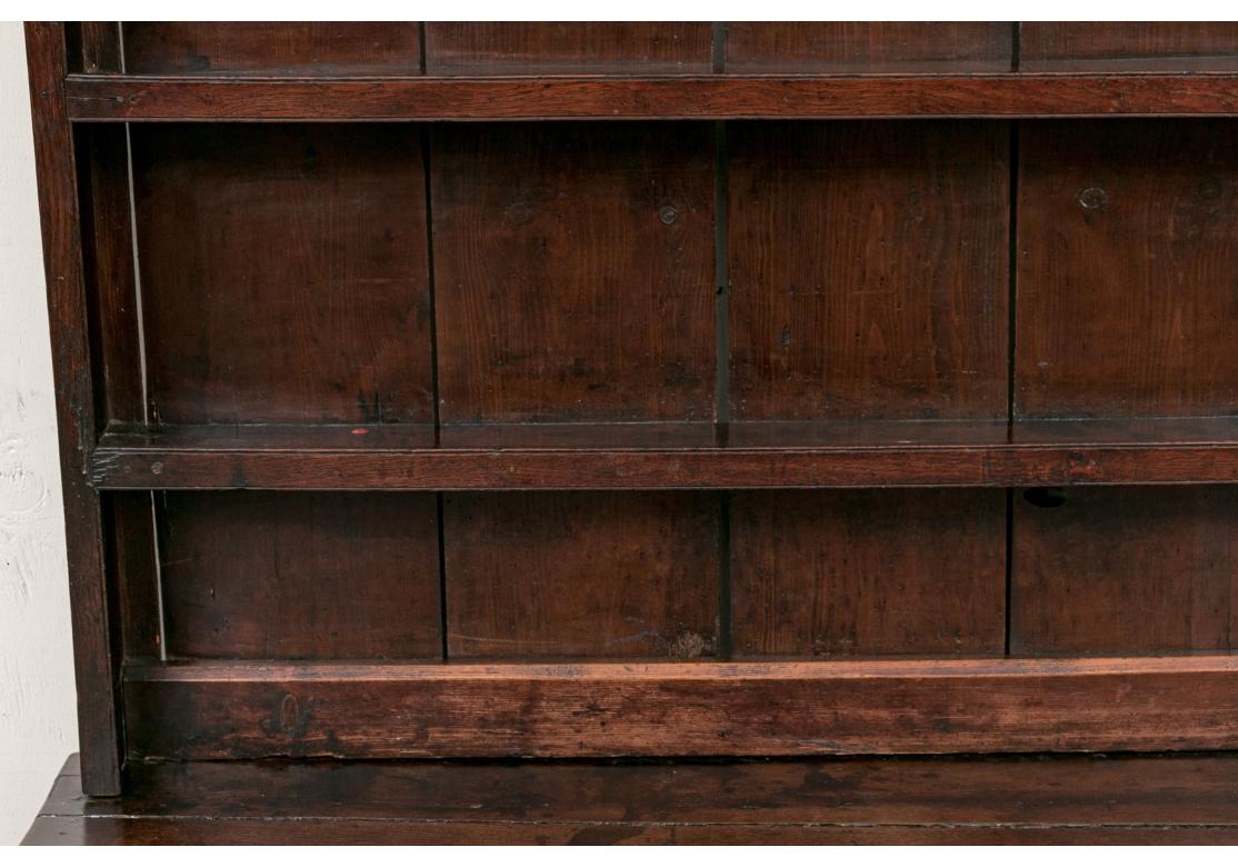 A traditional form stained Oak Welsh Hutch with dove-tail drawer construction .The oversized plate rack top resting on a sideboard base fitted with three short drawers raised on column supports above an open storage shelf, raised on block feet.