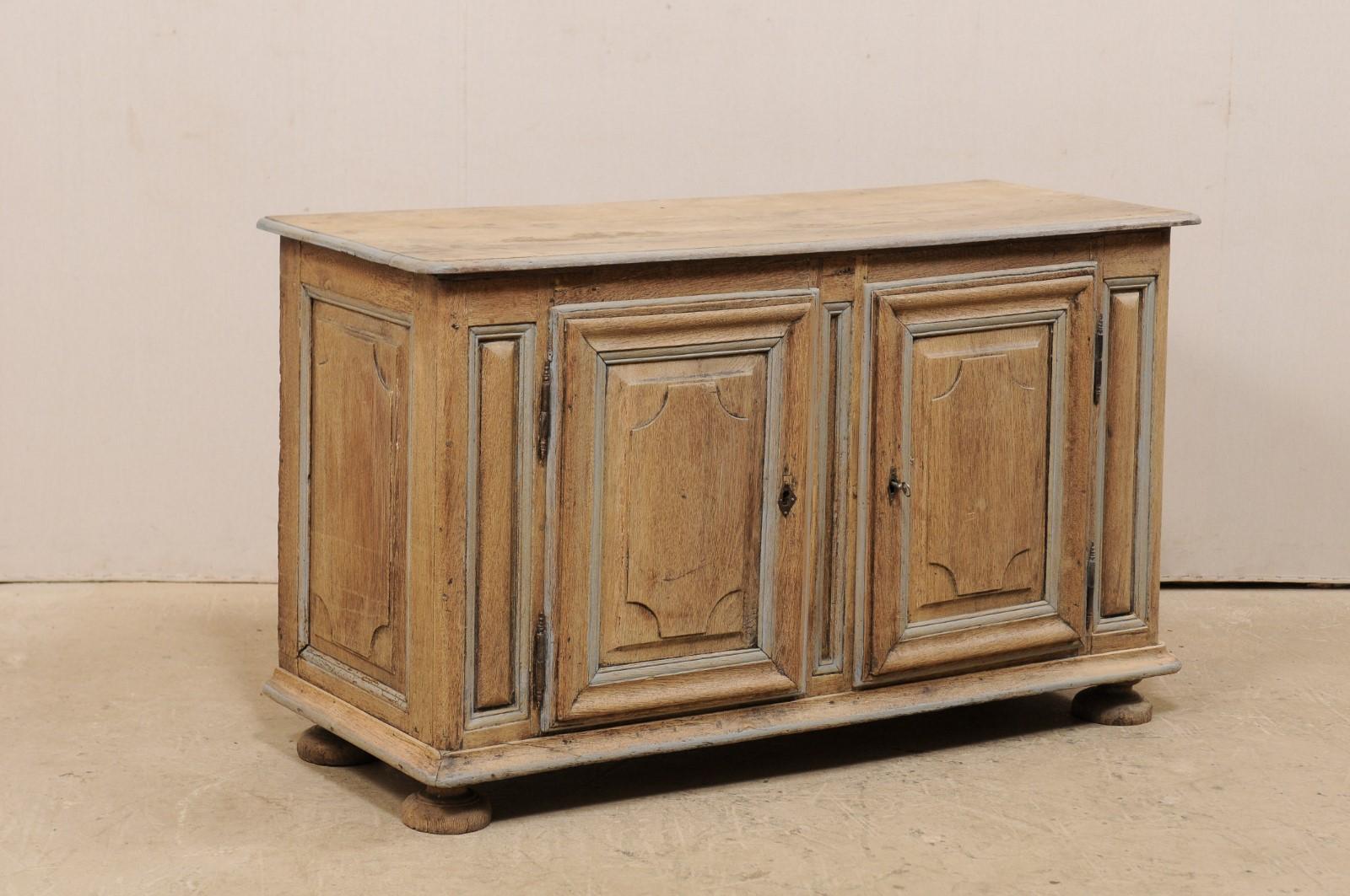 A French bleached oak console cabinet from the 18th century. This antique cabinet from France features a rectangular-shaped top with rounded front corner edges, which rests above a case of fitted with a pair of doors. Each door is adorn in heavily