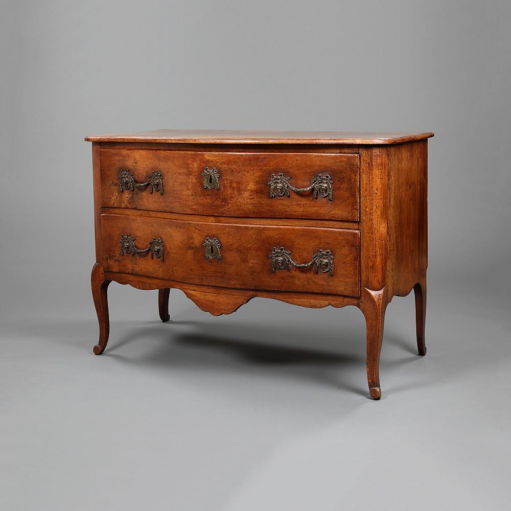 An 18th century French fruit wood serpentine commode made by Jean-François Hache, with two deep drawers, brass handles and escutcheons, raised upon cabriole legs with scroll feet.