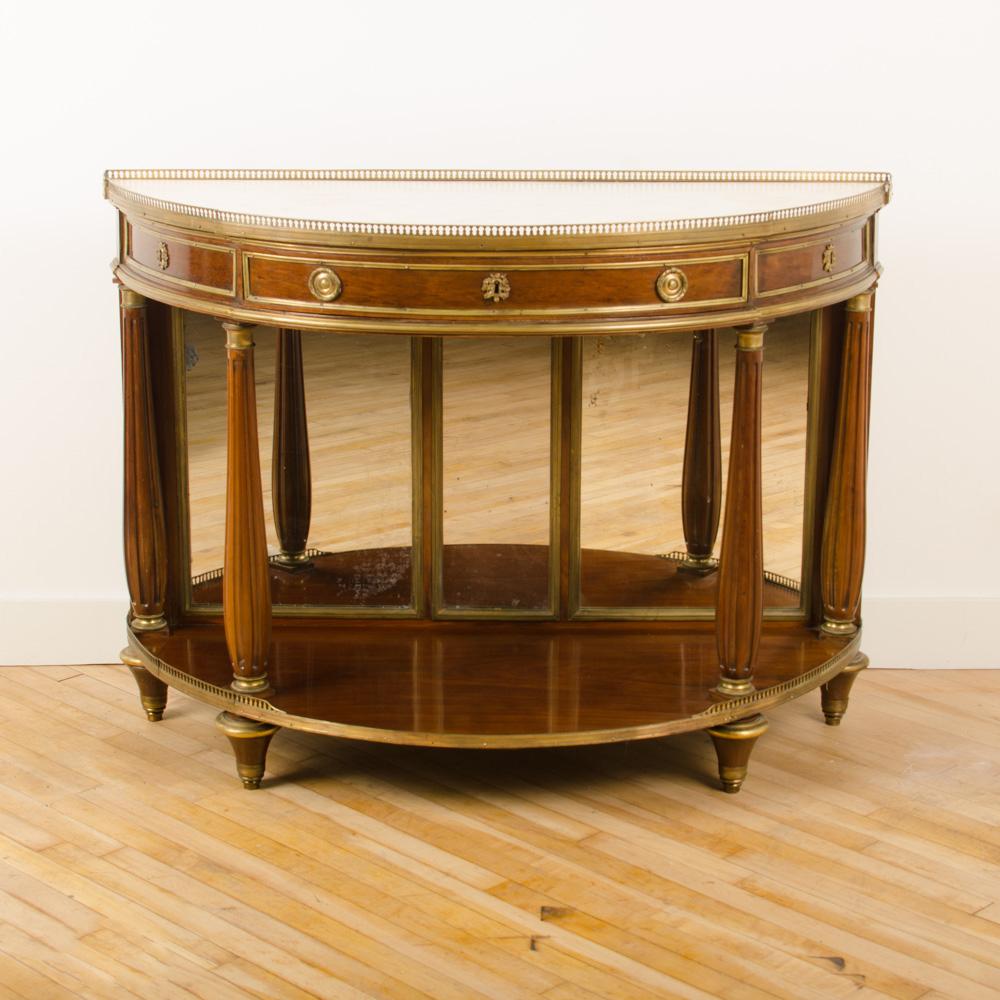 An eighteenth century French demilune mahogany server with marble top with brass accent gallery along the top and large central drawer that locks. Two small side drawers.