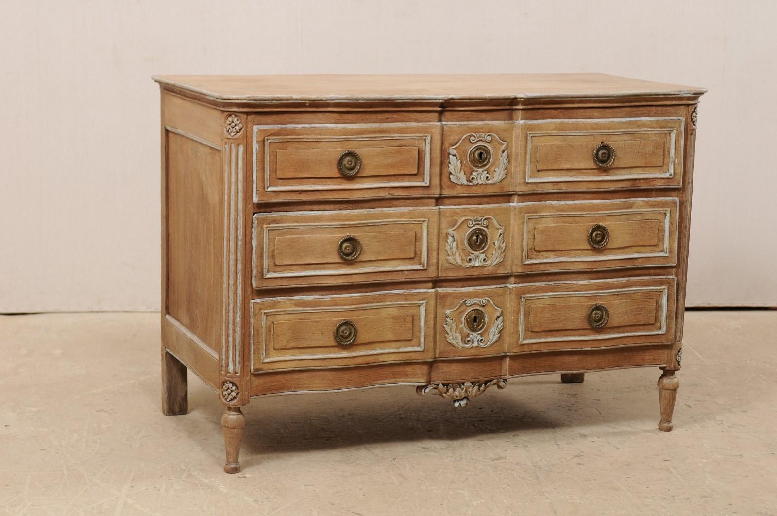 A French neoclassical carved serpentine-front chest of drawers from the 18th century. This antique commode from France features a rectangular shaped top with serpentine front lines, which mimic the movement of the case beneath. Front side posts are