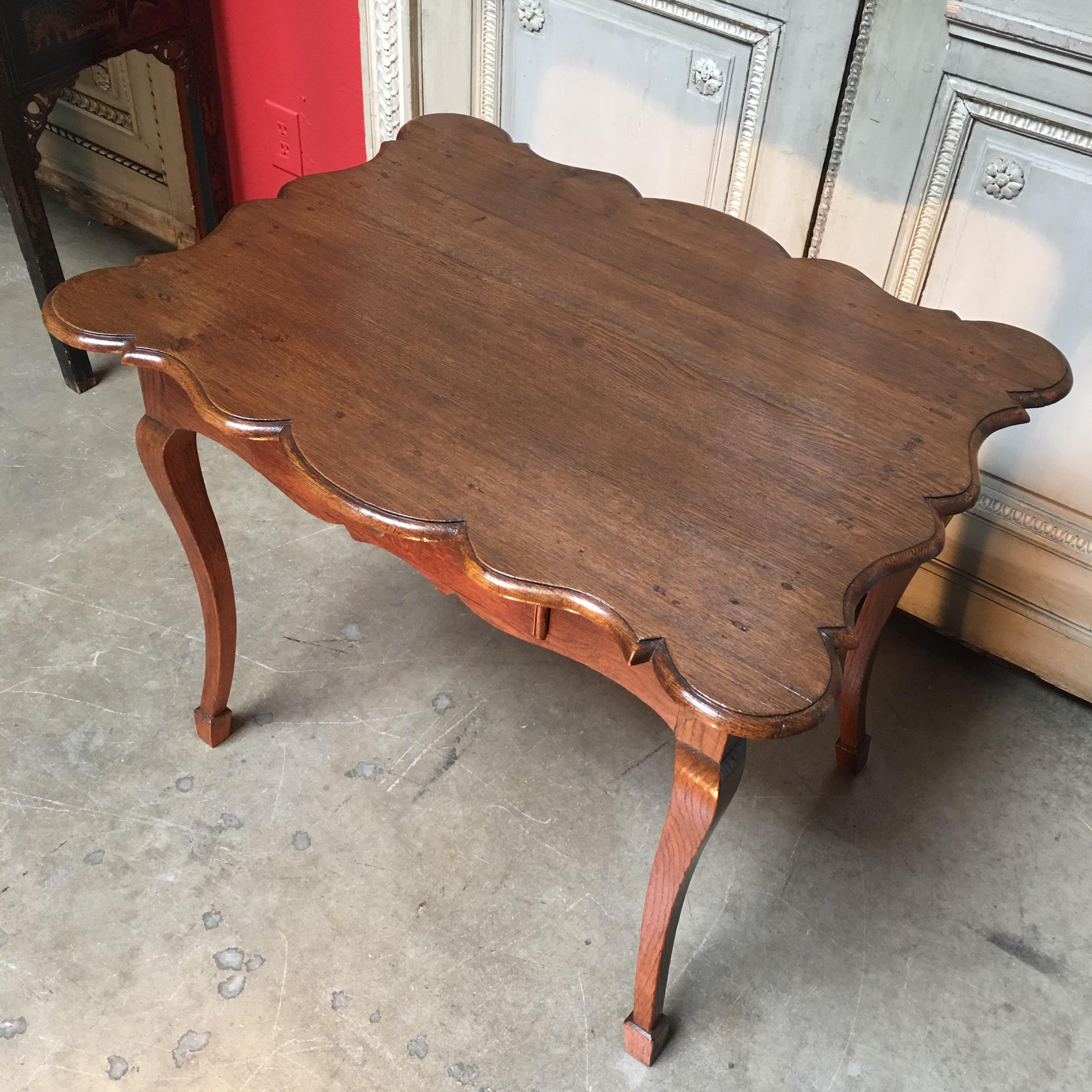 An 18th century French country Louis XV style writing table-end table. This lovely oak table features a scalloped shaped top, one drawer and cabriole legs. 