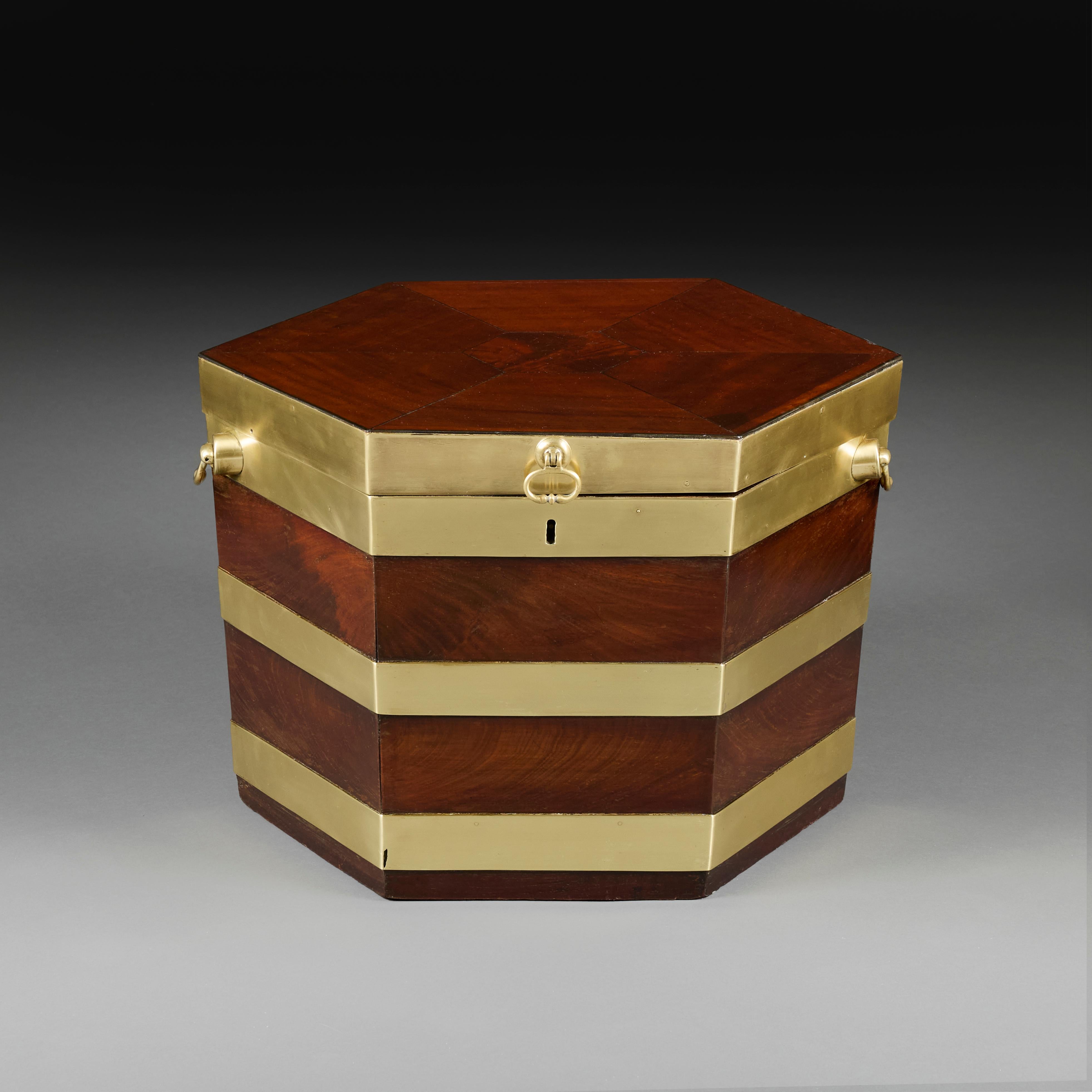 England, circa 1750

A mid eighteenth century mahogany and brass bound cellarette, the top lifting to reveal four circular apertures for bottles, with brass carrying handles.

Height  37.00cm
Width  53.00cm
Depth  45.00cm