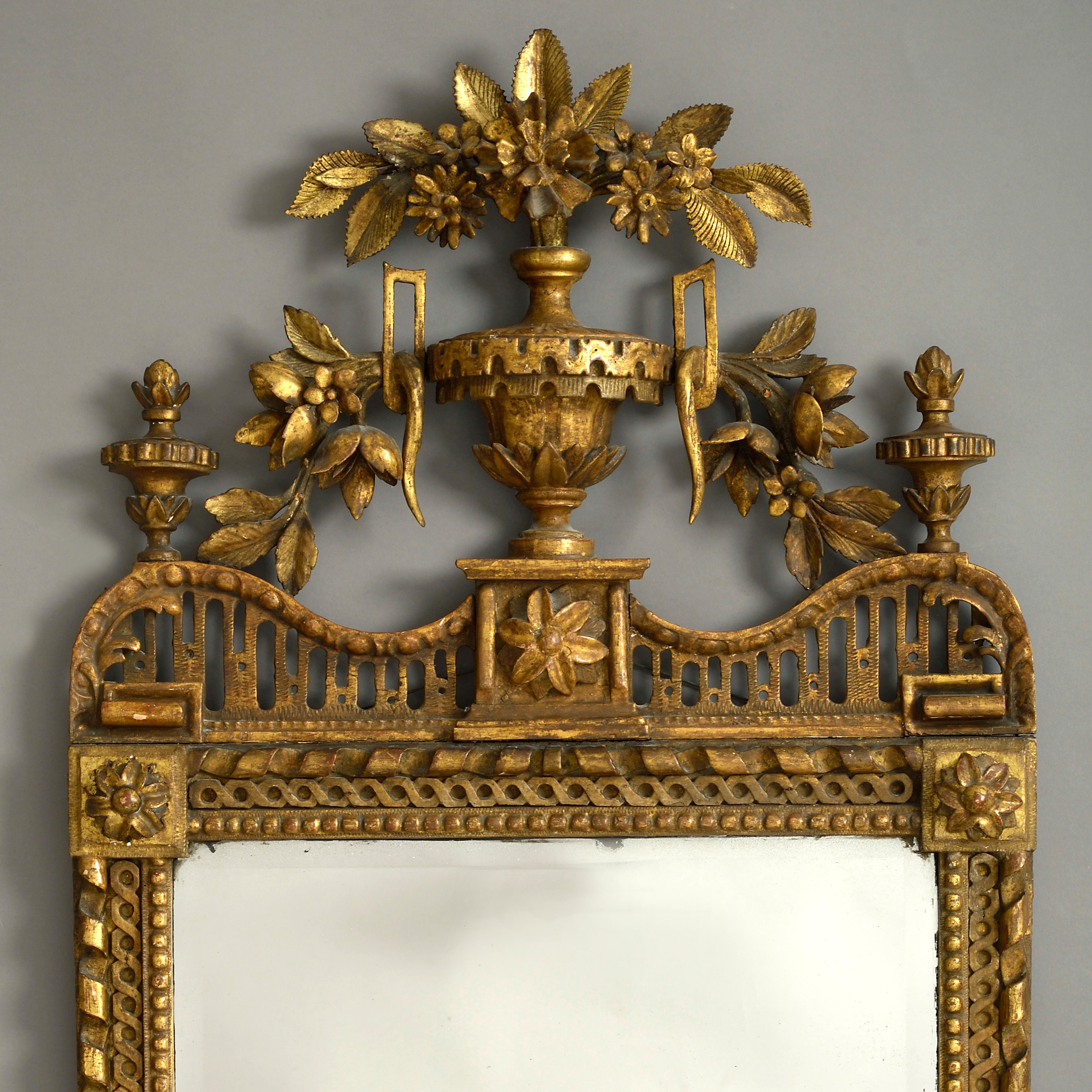A fine late 18th century pier mirror, the intricately carved giltwood frame surmounted by a floral cresting, a classical urn and foliate garlands, the corners having carved paterae, all housing a beveled mercury plate.
