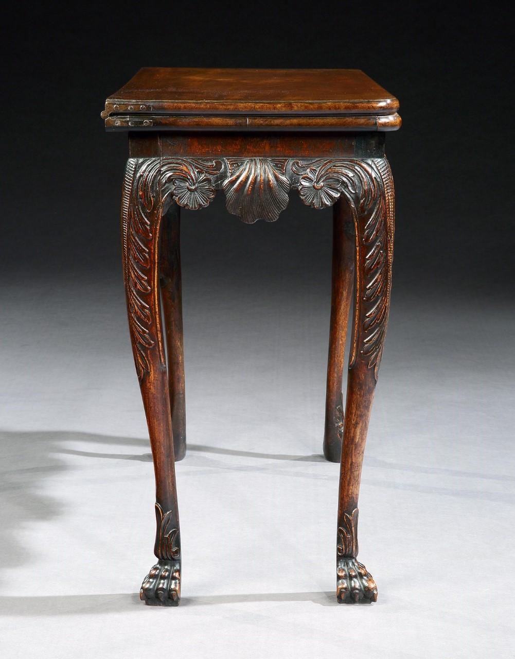 A superbly carved 18th century Irish walnut games table. The rectangular turnover top above a well carved frieze, with a central scallop shell, flanked by flowing acanthus, resting on acanthus carved cabriole legs with bold paw feet.