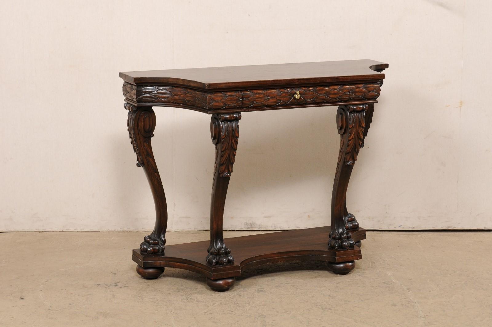 An Italian beautifully carved walnut console table, with lower tier platform shelf, from the 18th century. This antique table from Italy is comprised of rich walnut wood that has been exquisitely carved in a foliate motif about the apron, and its