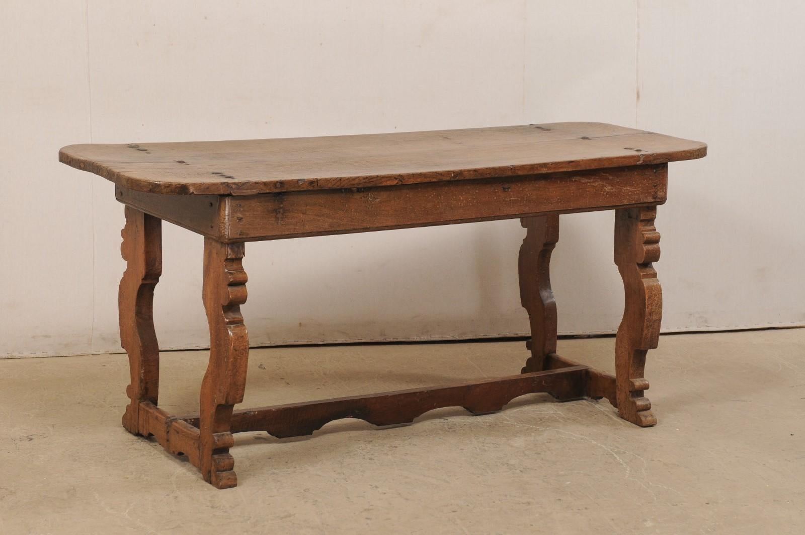 An Italian console table, or desk, with single board top and trestle legs from the 18th century. This antique chestnut wood farm table from Italy features a single wood board plank top, attached to the cleanly designed apron with fabulous old thick