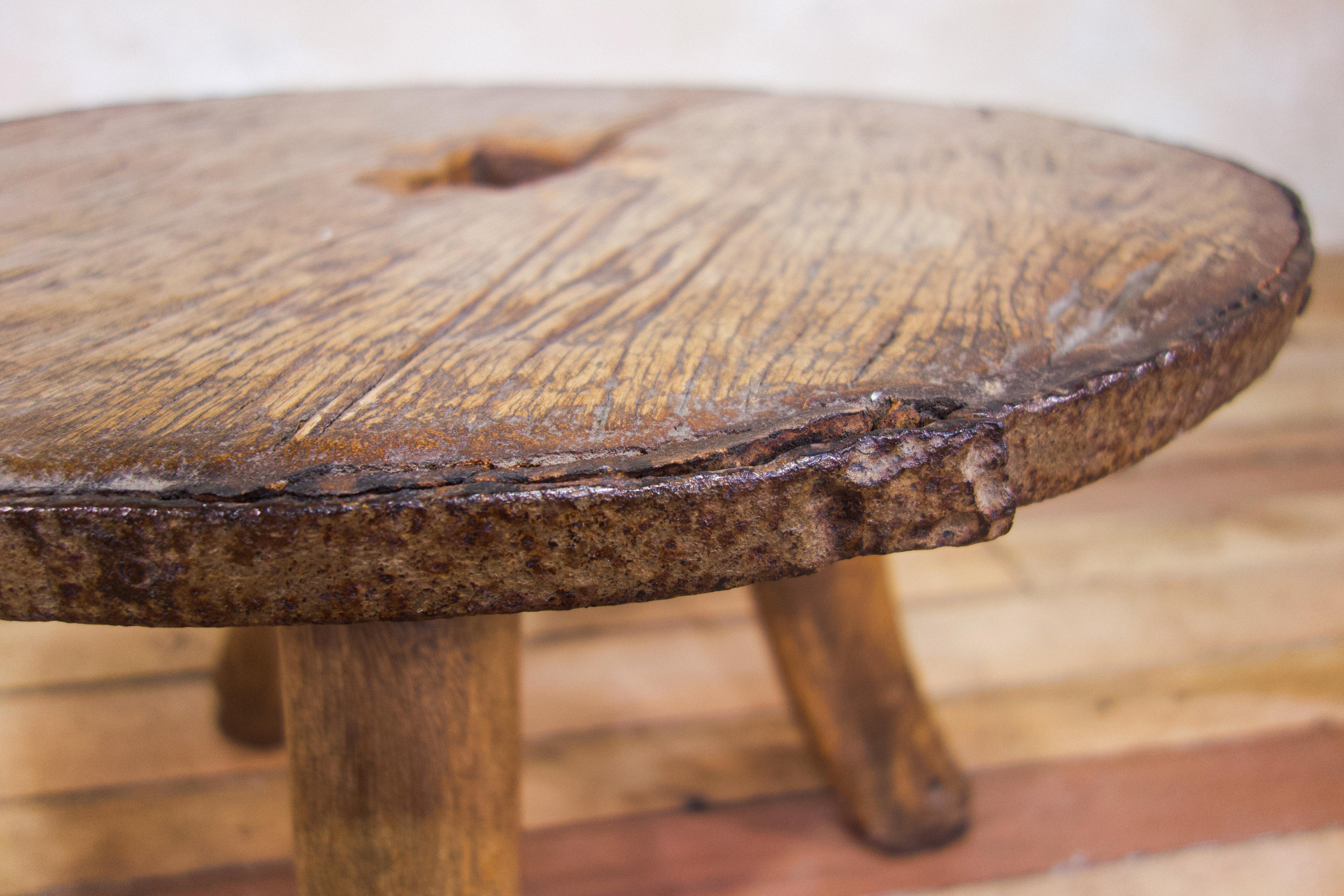 An organic 18th century and later Ox wheel - low table. Displaying a weathered patina witnessing years of use since the early 18th century. This table utilises an 18th century ox cart-wheel top, retaining its original iron bound banding. Raised on