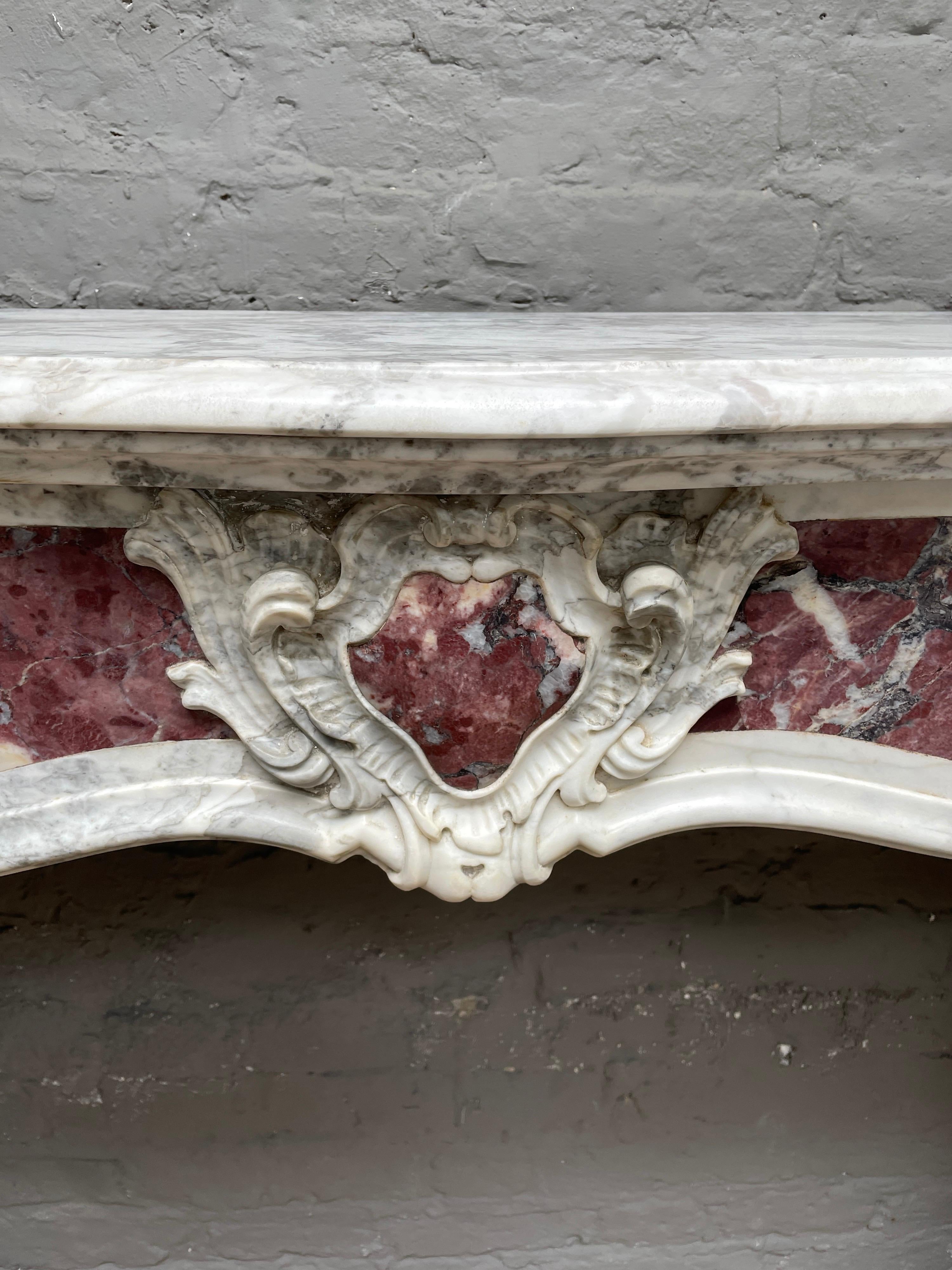 A charming and very well executed late 18th century Provincial Louis XV style fireplace in Calacatta and Breche Violette marbles. The jambs with paneled Breche Violette and fine carved scrolled Acanthus supporting a serpentine frieze again paneled