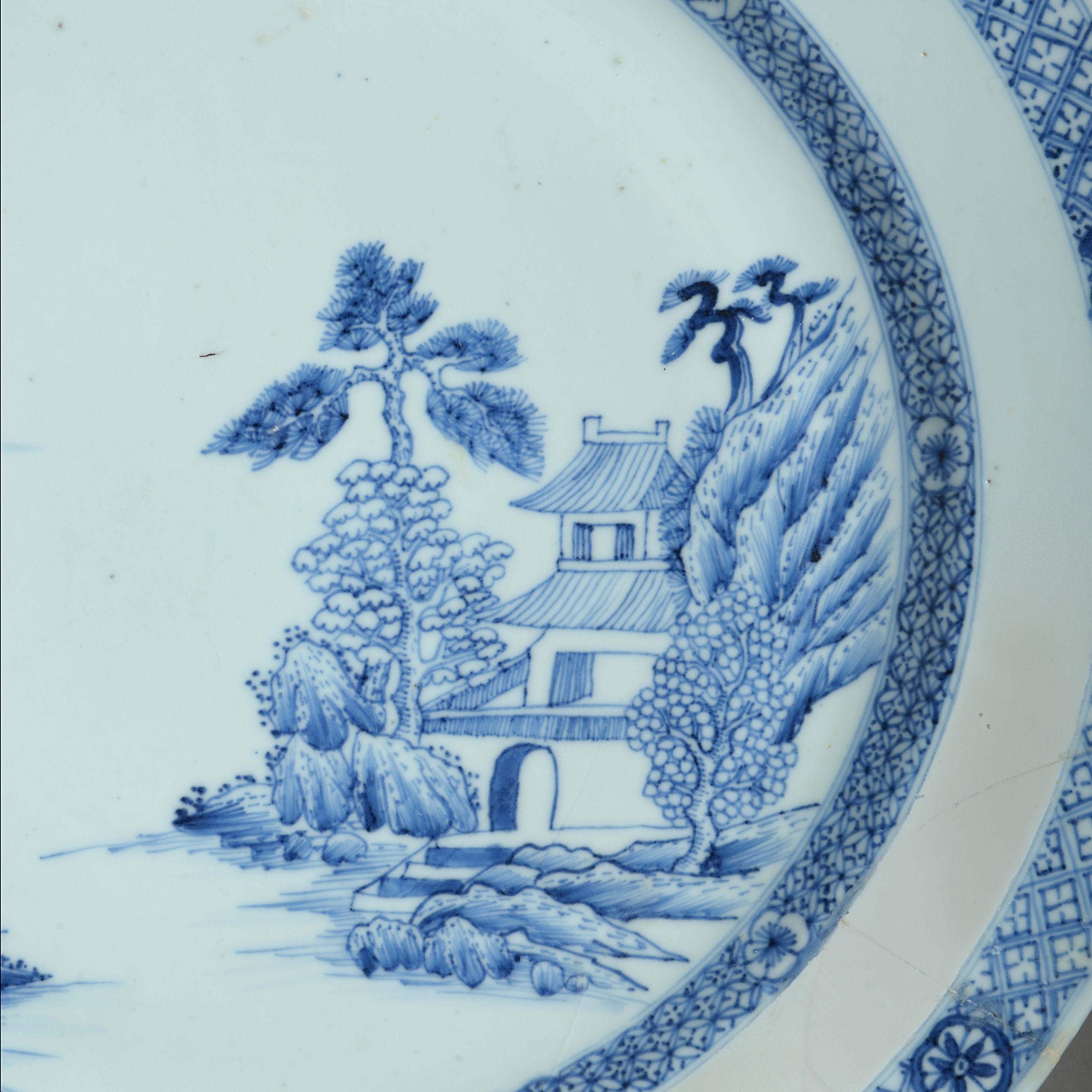 An 18th century blue and white porcelain charger, decorated with an imaginary landscape and foliate borders.
 