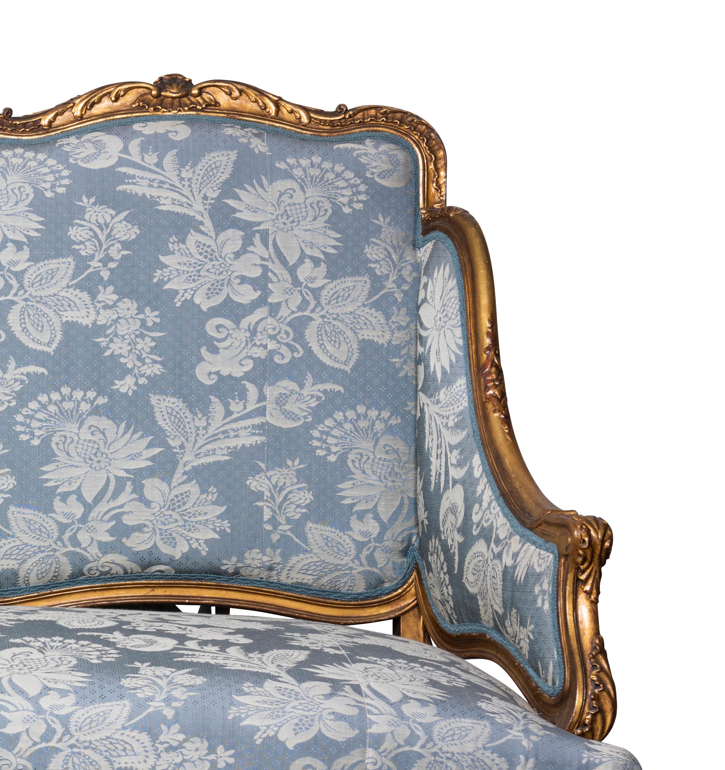 The exposed giltwood frame richly decorated with rocaille palms and foliated reliefs, the cartouche back, seat and articulated arms upholstered in monochromatic northern Italian floral silk, the whole supported on eight cabriole legs united by