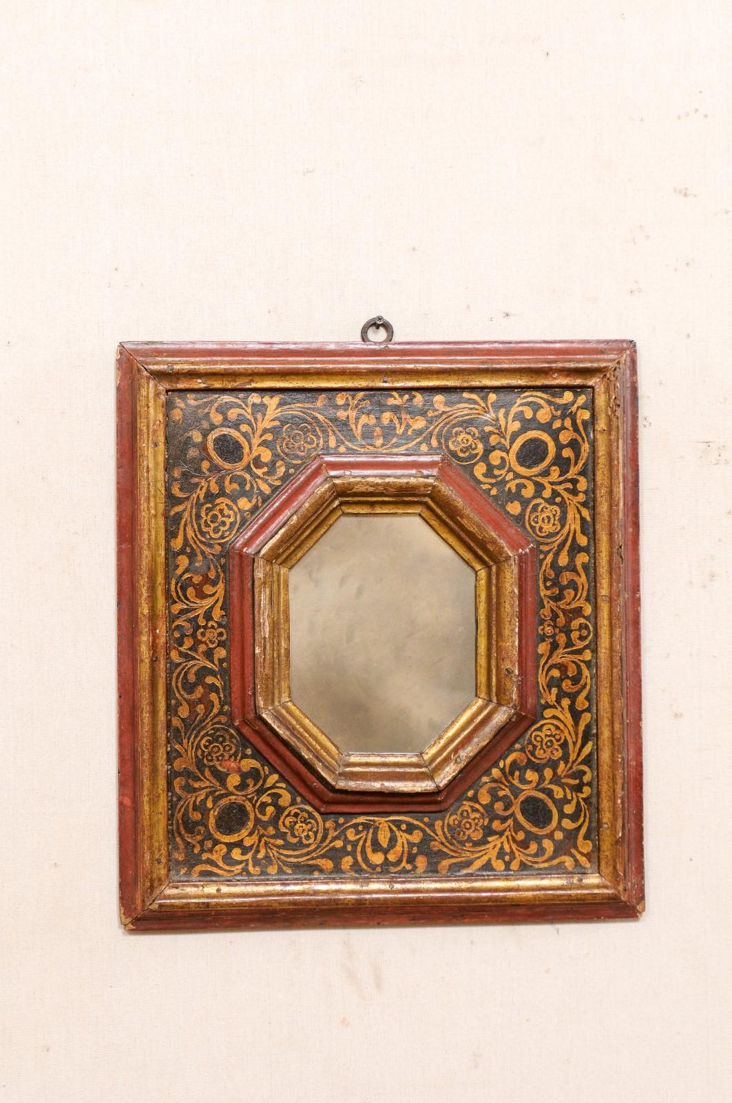 A Spanish hand-painted accent mirror from the 18th century. This antique wall decoration from Spain is nearly-square in shape, with a molded frame, with an inner surround adorn in a hand-painted scrolling leaf motif, about a central mirror housed