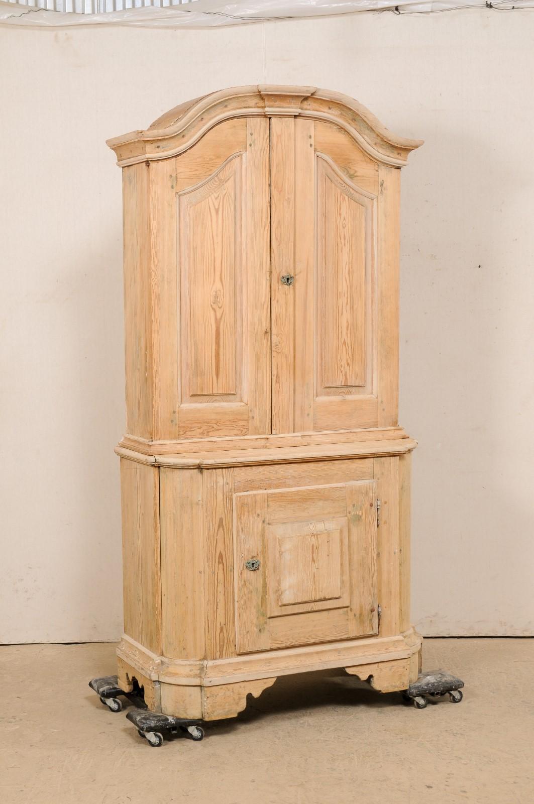 A Swedish period Rococo painted wood tall cabinet from the 18th century. This antique cabinet from Sweden is crowned by a gracefully arched pediment cornice at top, has beautifully carved raised panel doors, and is presented upon curvy-carved